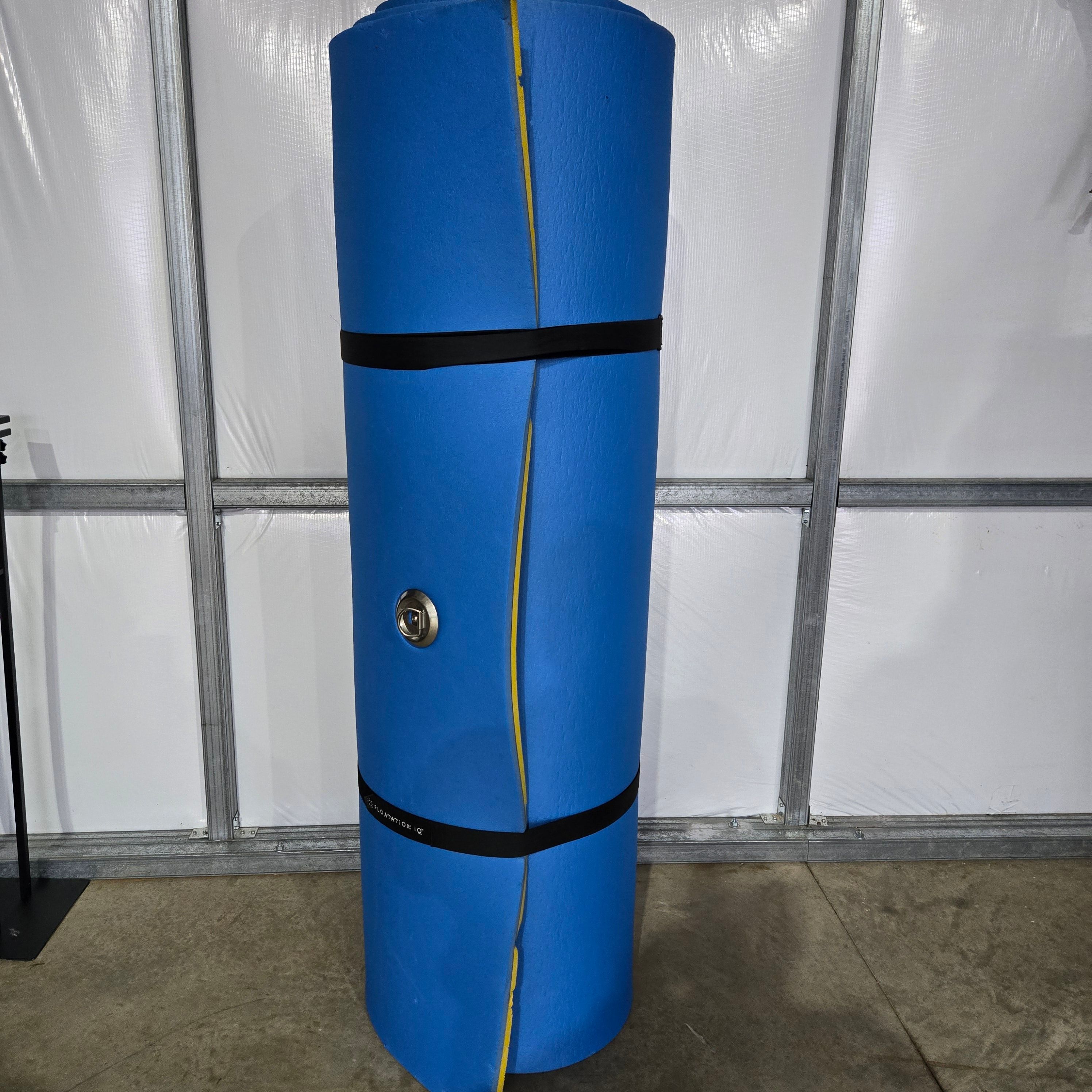 A rolled-up blue floatation device stands upright in a room with a concrete floor.
