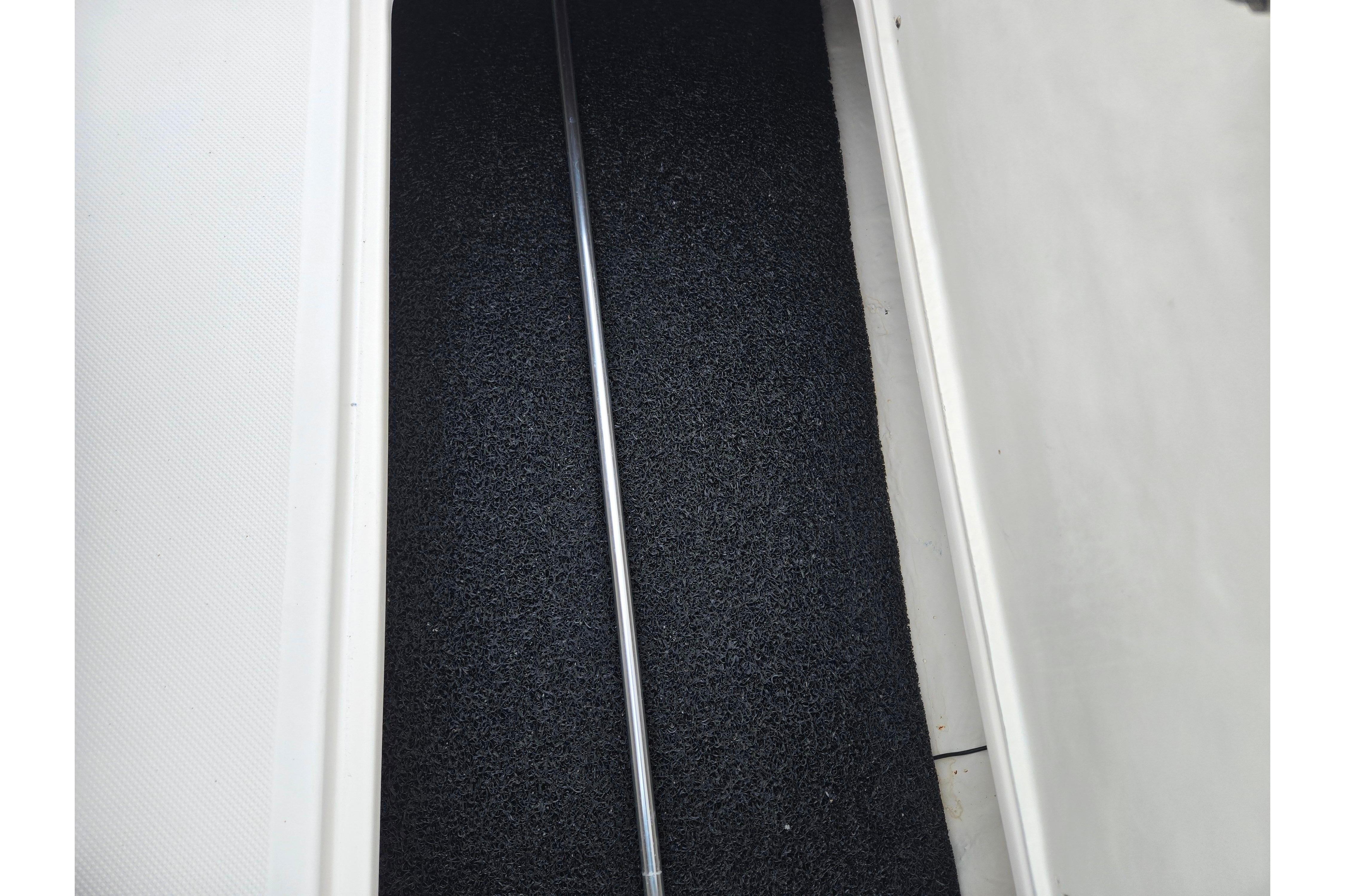 Storage compartment of 2015 Regal 1900 ES Bowrider boat with black mat lining.