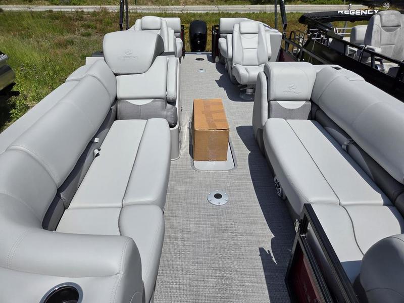 2025 Regency 230 DL3 pontoon boat interior with gray seating and a cardboard box on the floor.