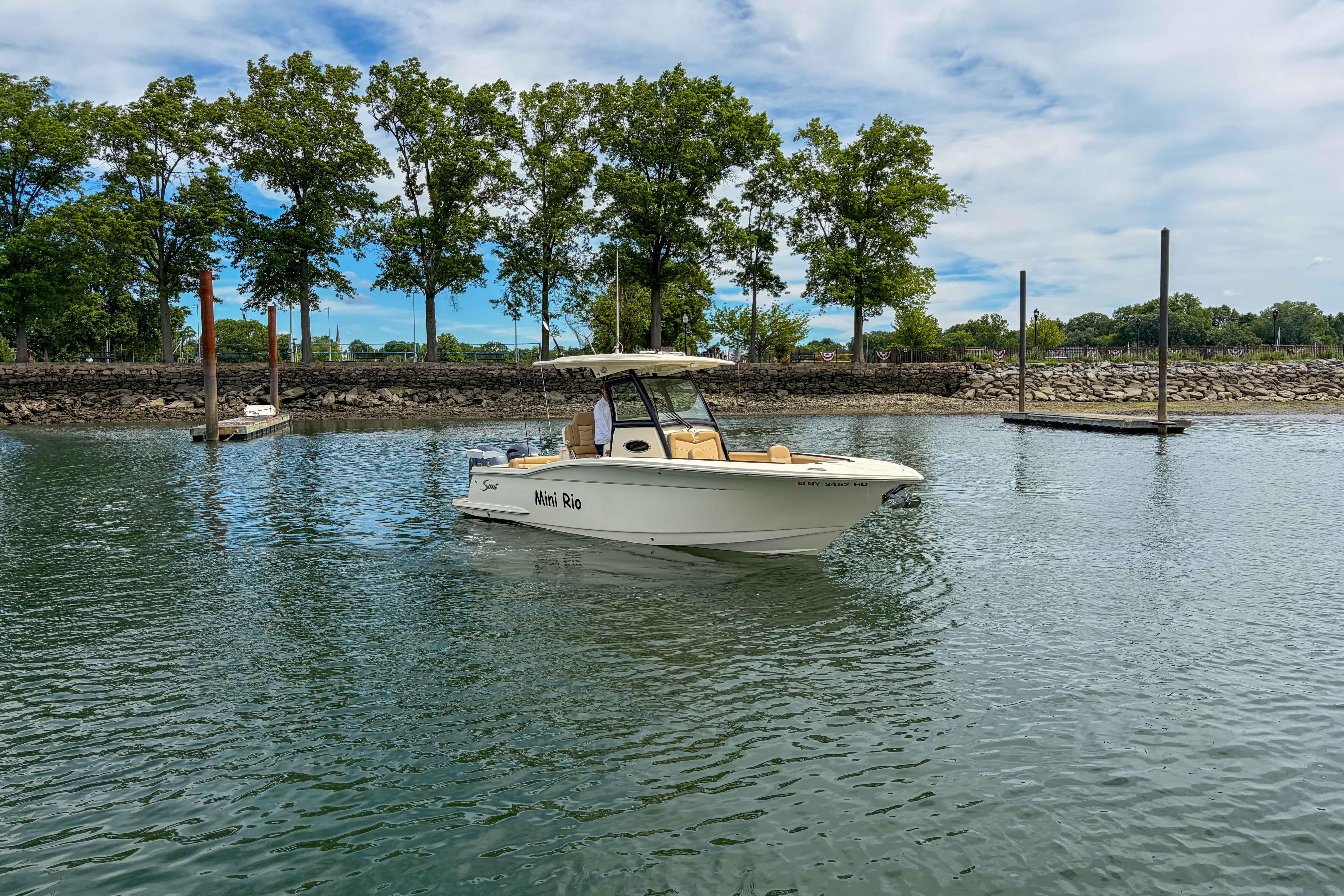 2020 Scout 255 LXF boat on calm water near a tree-lined shore.