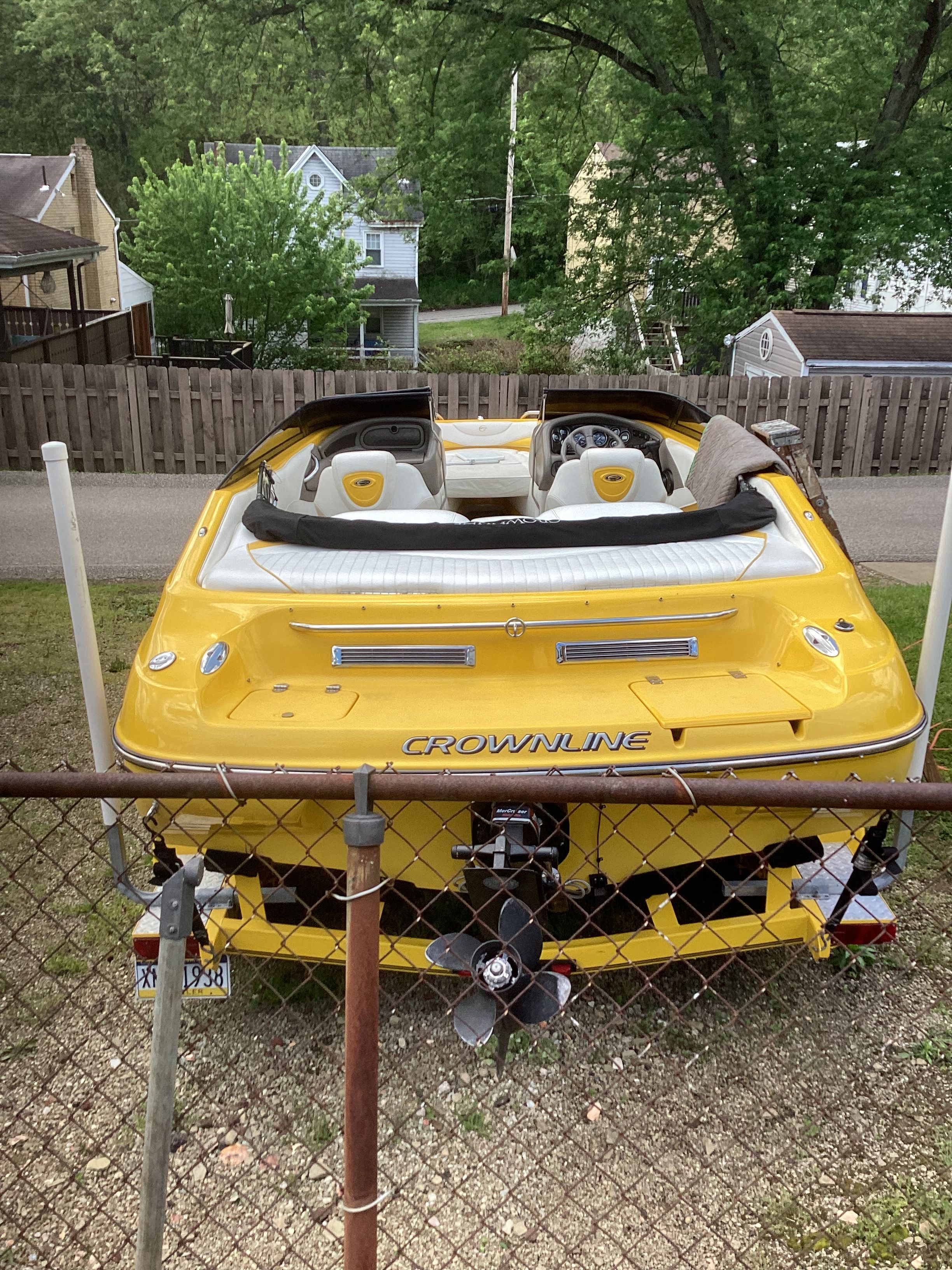Yellow 2005 Crownline 202 BR LPX boat parked in backyard.
