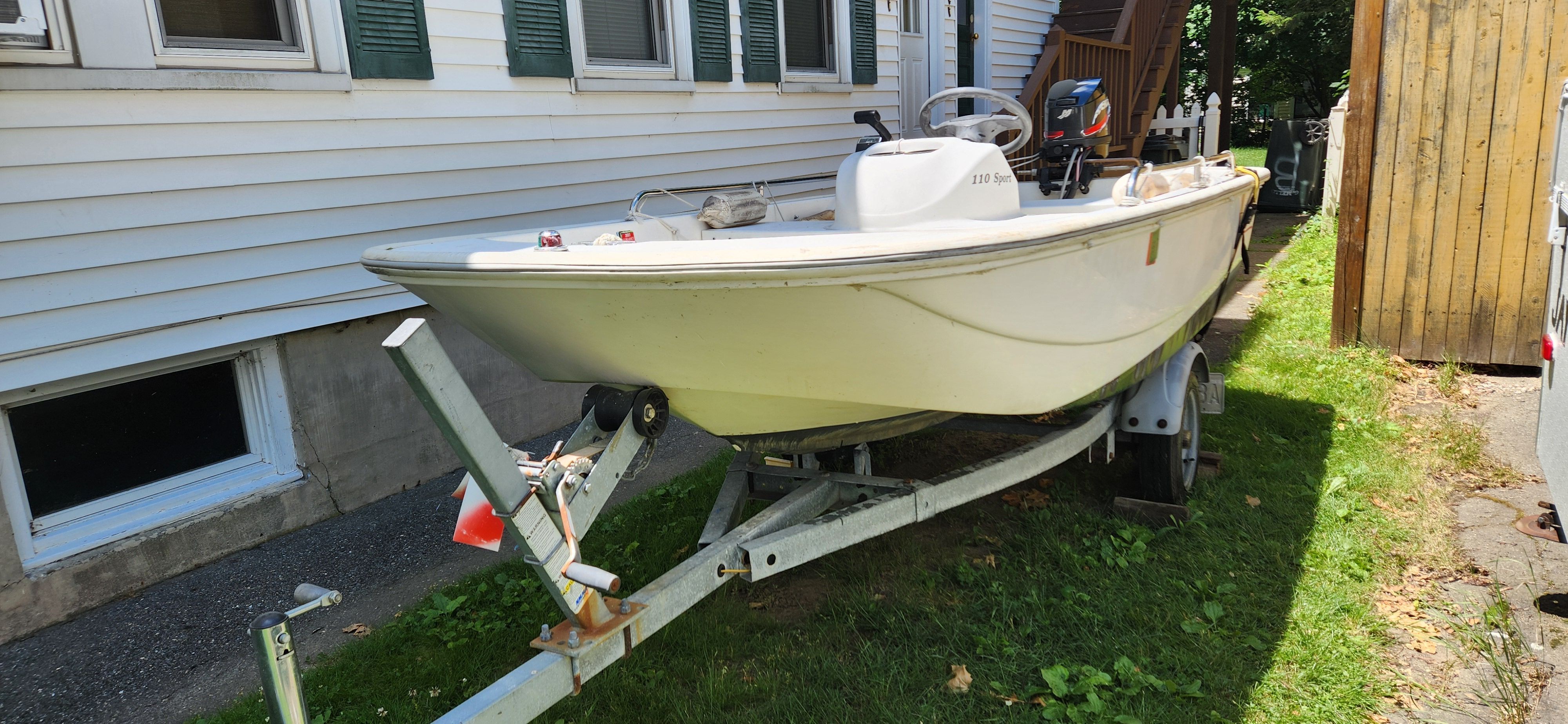 A Boston Whaler 110 Sport boat on a trailer beside a building.