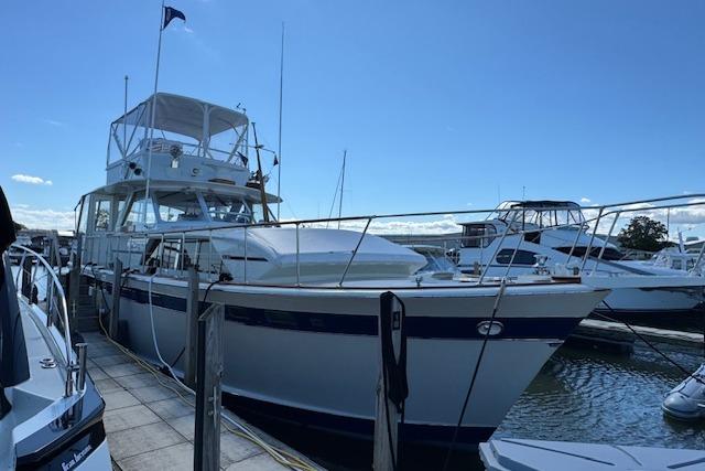 1974 Chris-Craft 47 Commander yacht docked at a marina under a clear blue sky.