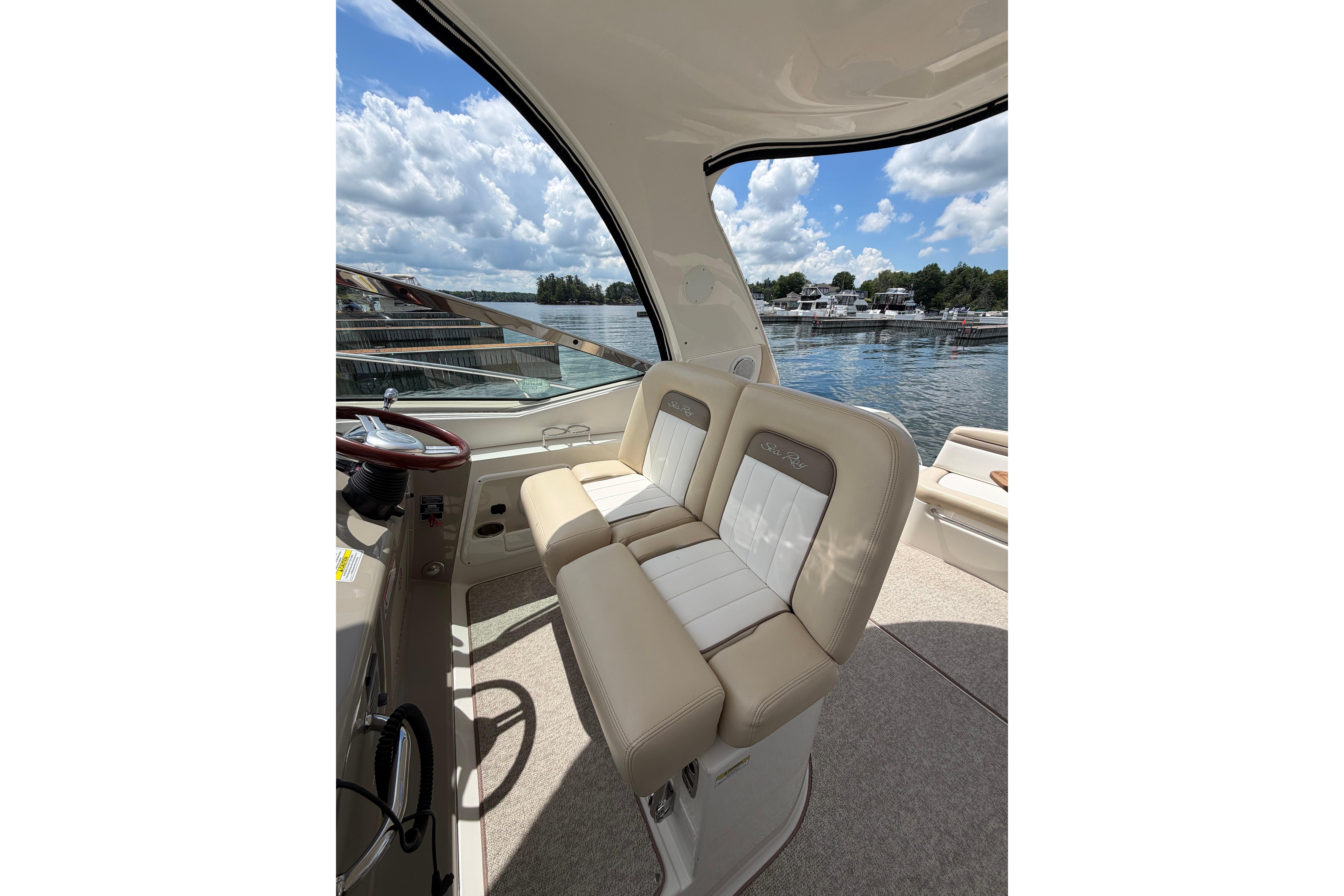 2012 Sea Ray Sundancer 370 cockpit with beige seating, overlooking a serene waterfront.