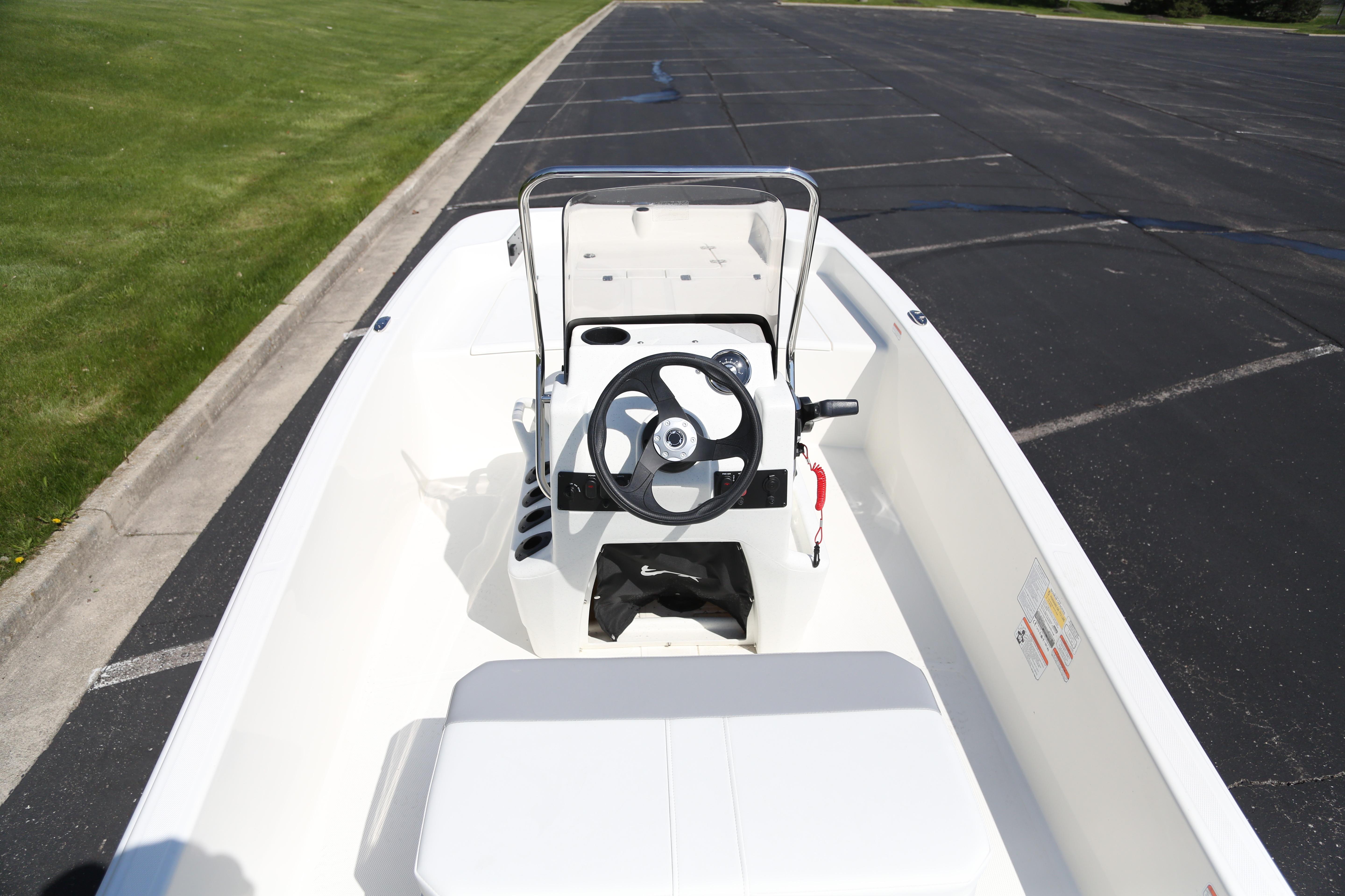 2026 Mako Pro Skiff 15 CC boat interior with steering wheel, parked on pavement.