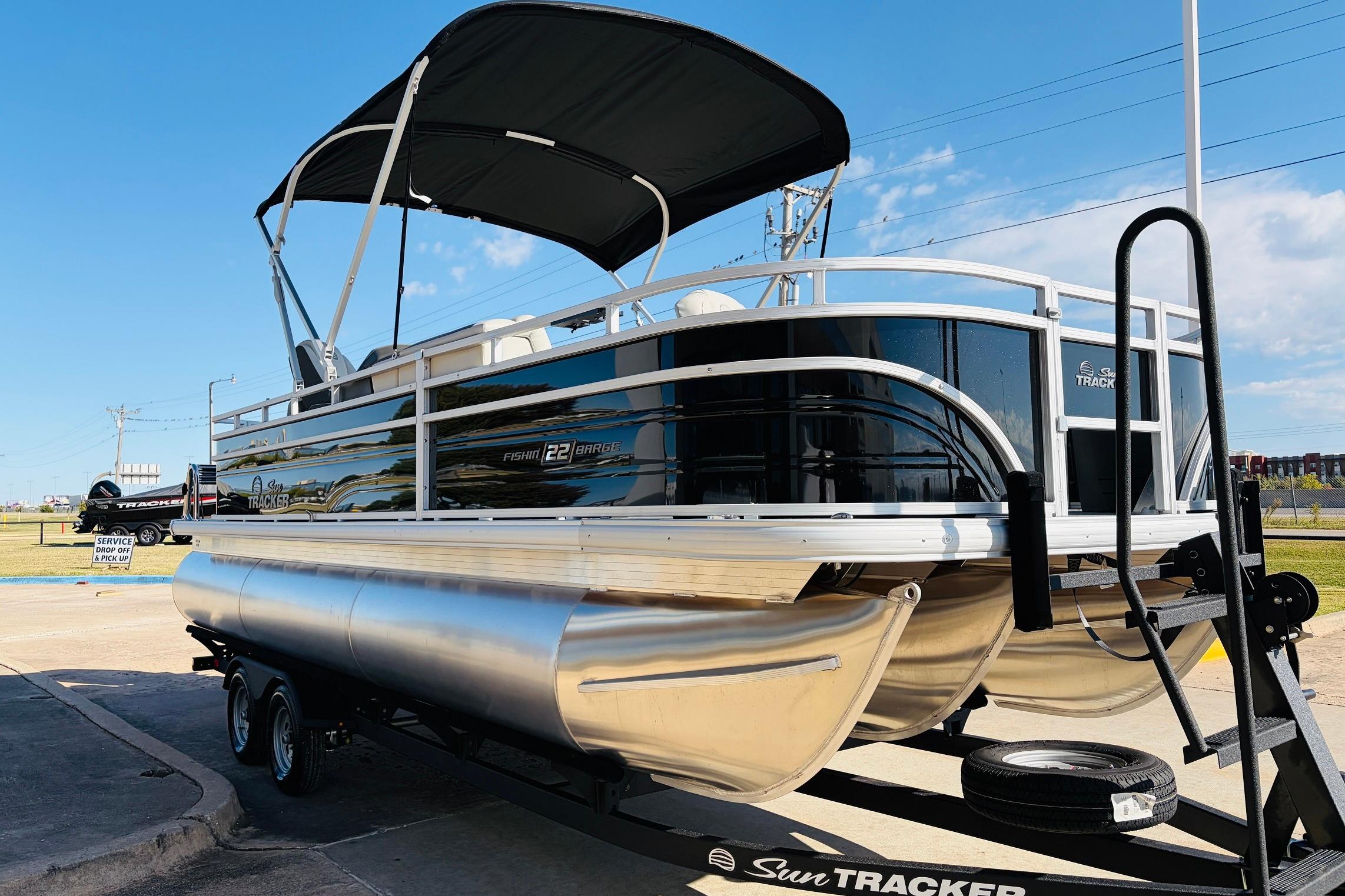 2026 Sun Tracker Fishin' Barge 22 XP3 pontoon boat on trailer, parked outdoors.