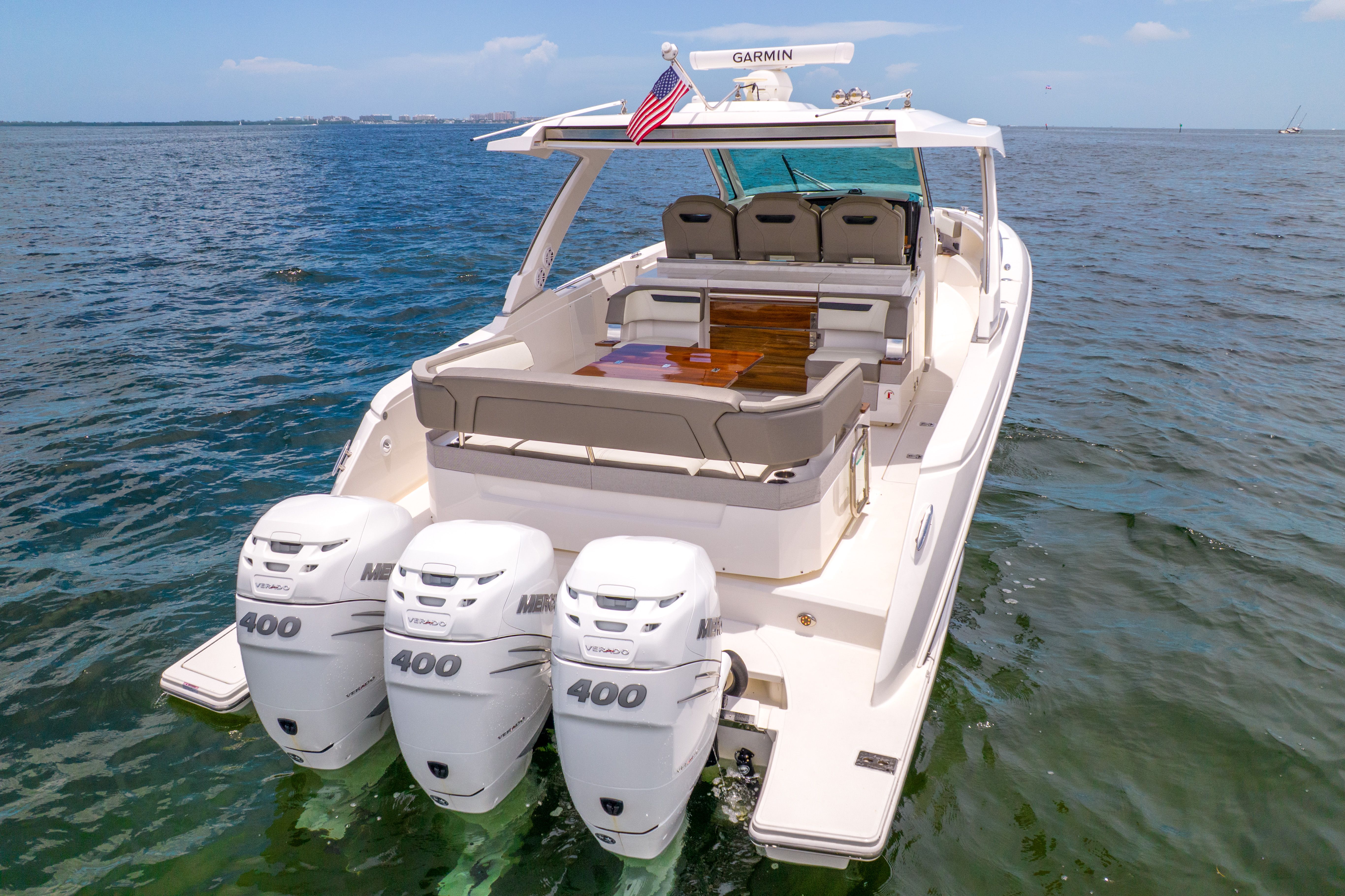 The 2023 Tiara Yachts 38 LS is on calm water, featuring three outboard engines.