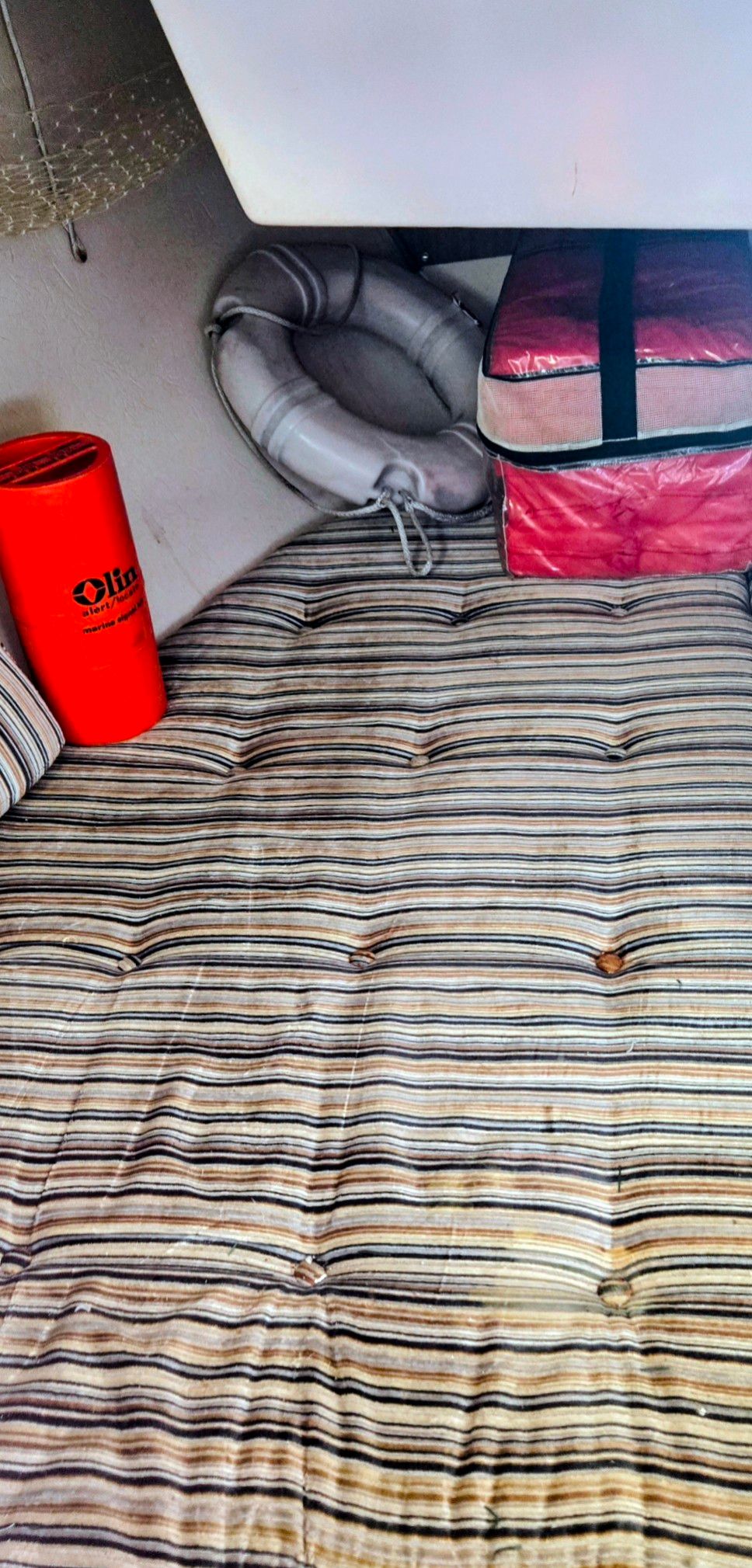 The image shows a cozy cabin with striped upholstery, a life ring, and a red container.