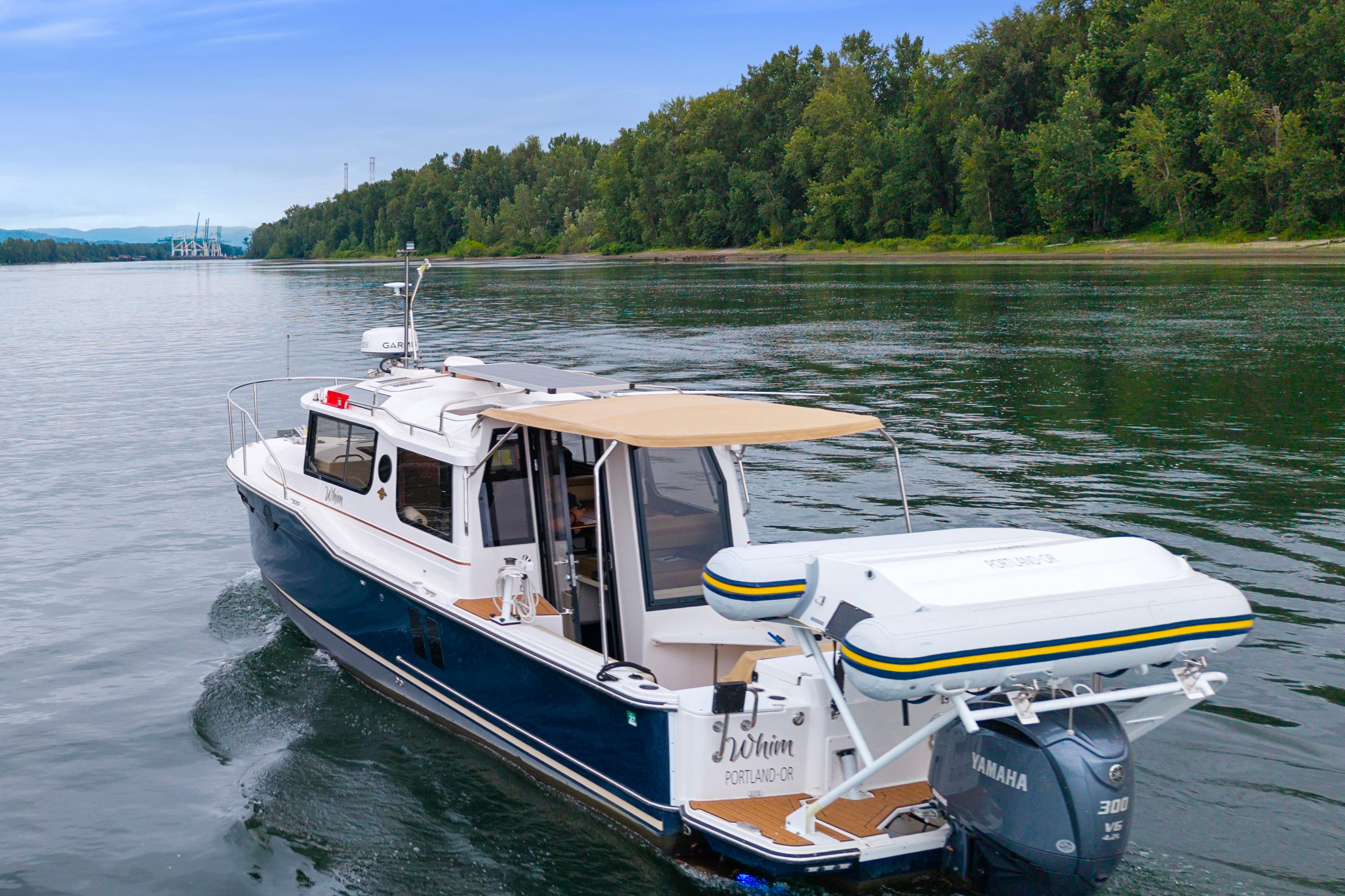 2022 Ranger Tugs R-27 cruising on a serene river, surrounded by lush greenery.