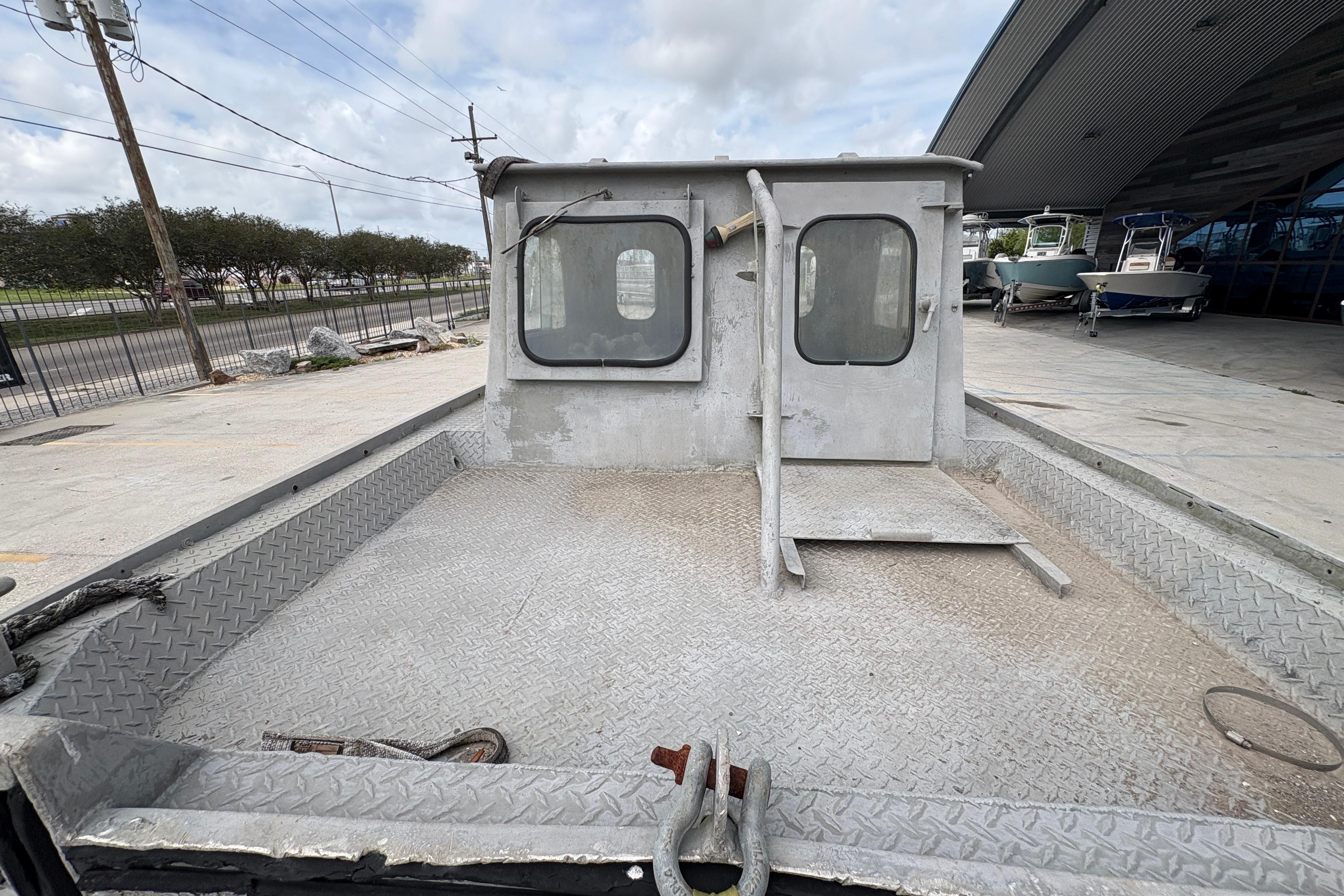 1972 Custom 23' work/push boat with metal deck and cabin, docked outdoors.