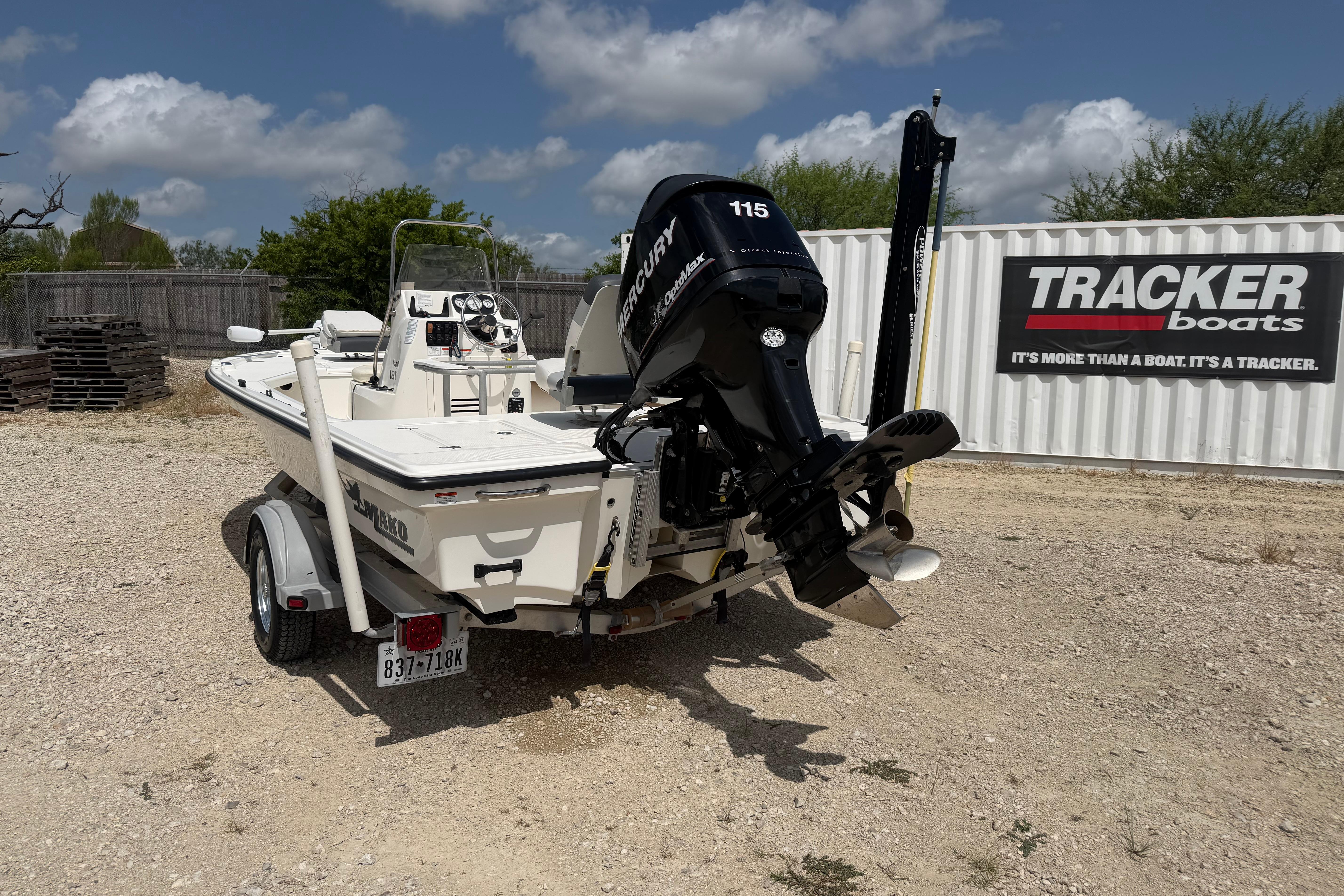 2012 Mako 18 LTS boat with Mercury engine, parked on gravel near Tracker Boats sign.