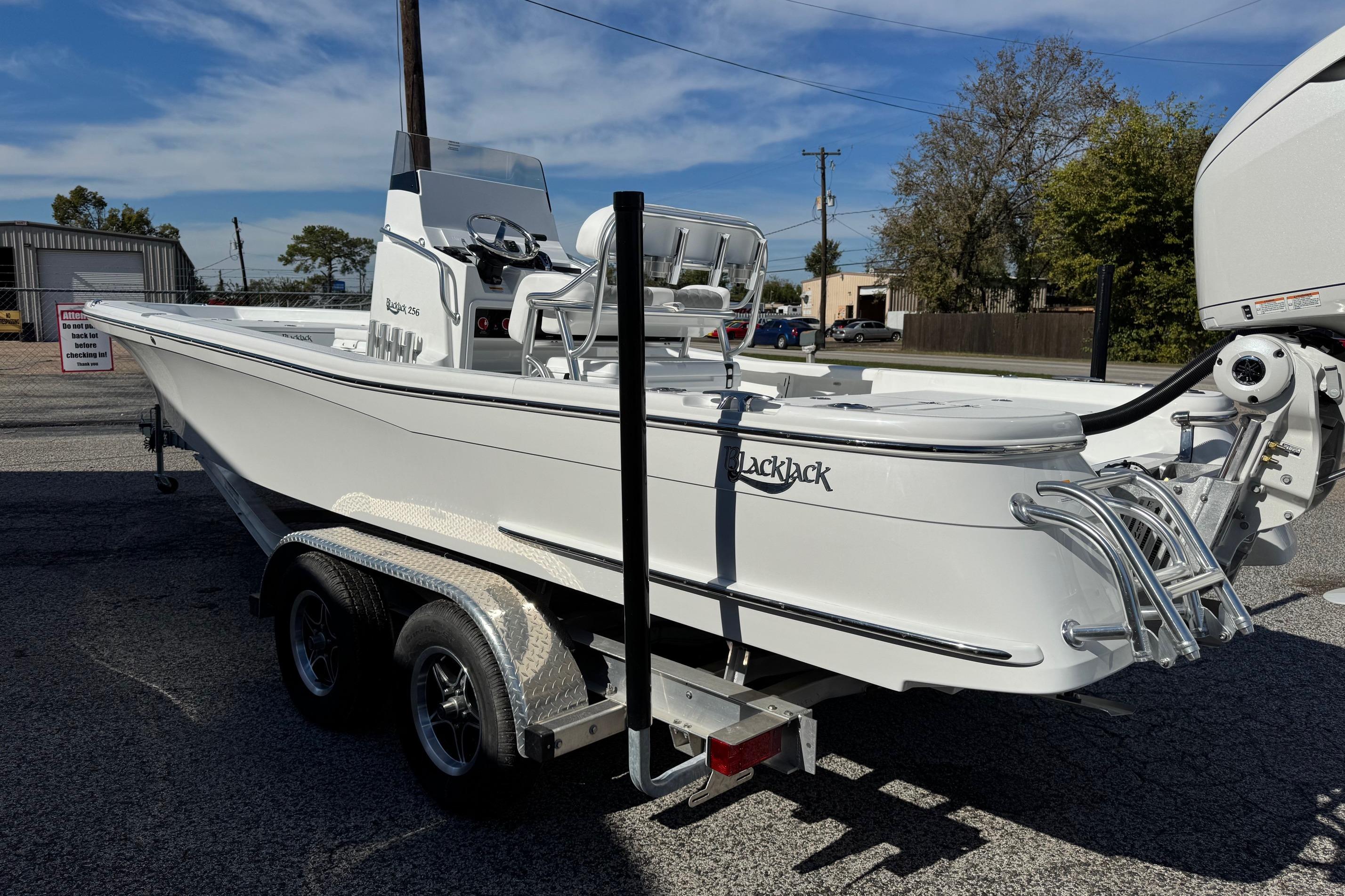 2026 BlackJack 256 Bay boat on trailer, parked outdoors under clear sky.
