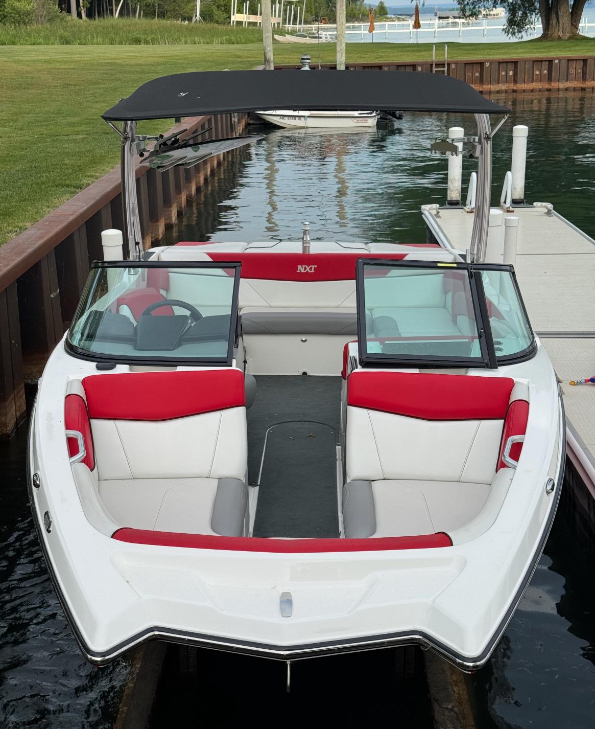 2017 MasterCraft NXT22 boat docked, featuring red and white seating, with a black canopy.