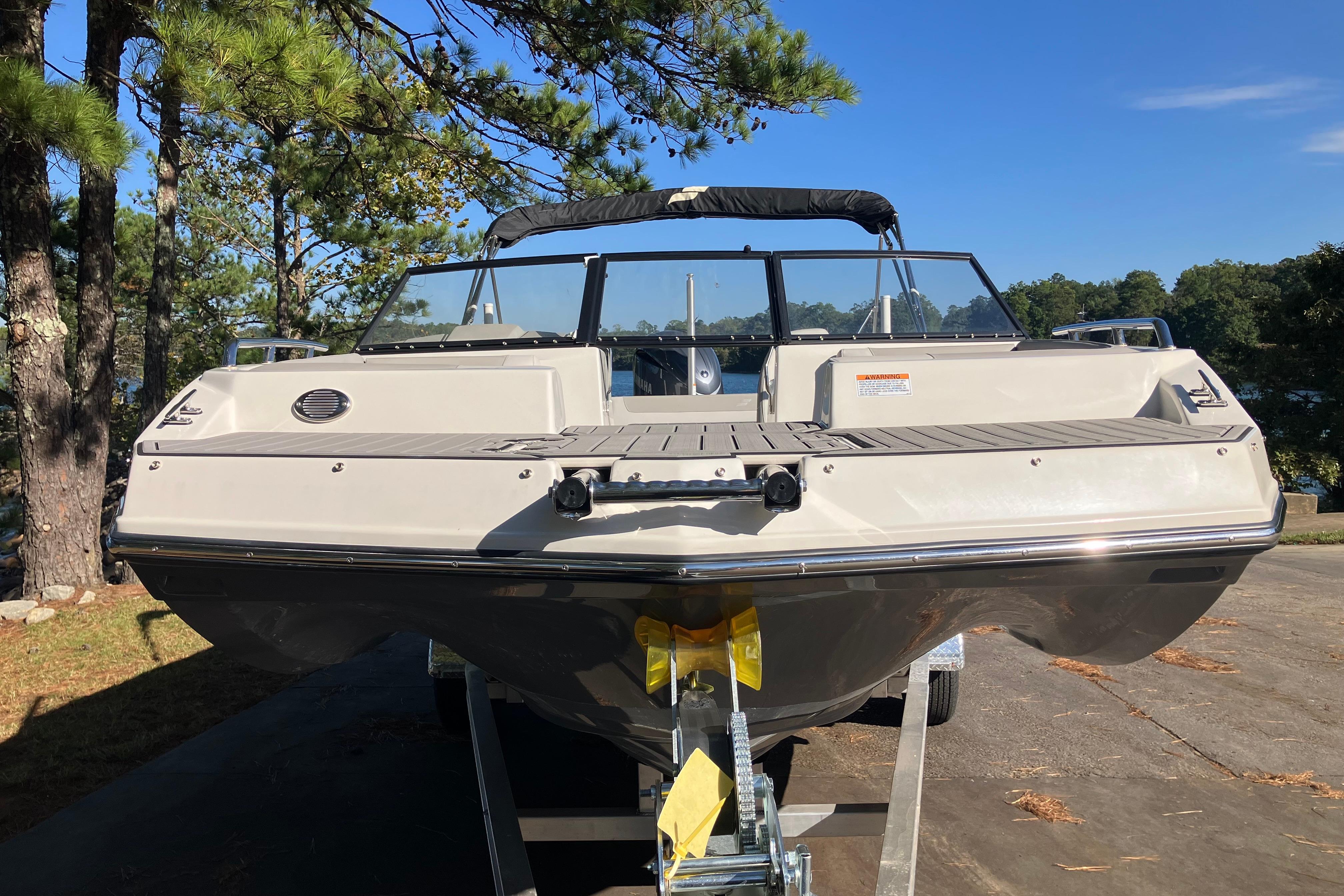 2025 Starcraft SVX 210 OB boat on trailer, surrounded by trees and clear sky.