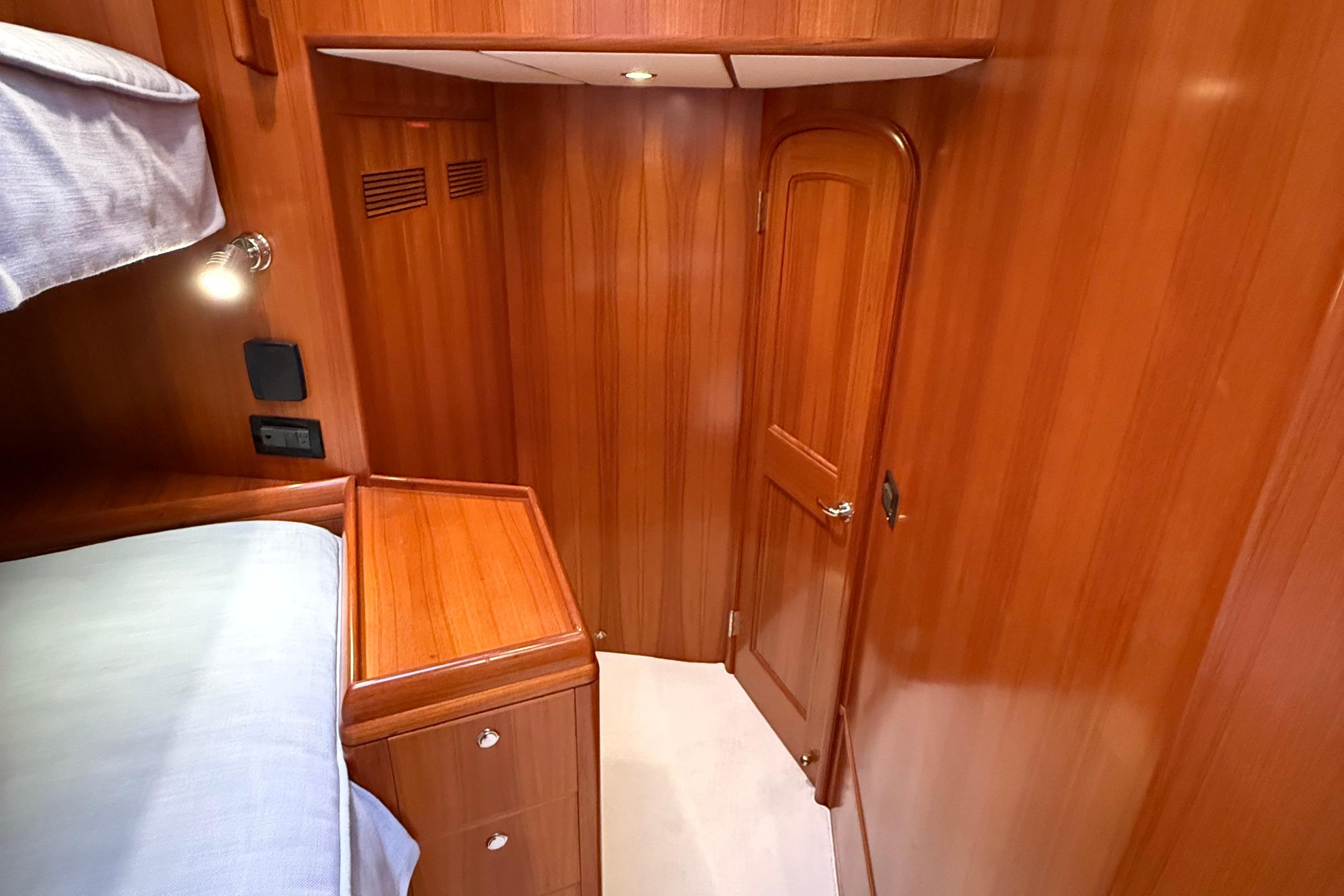 Luxurious wooden interior of 2009 Nordhavn N64 yacht cabin with bed and door.