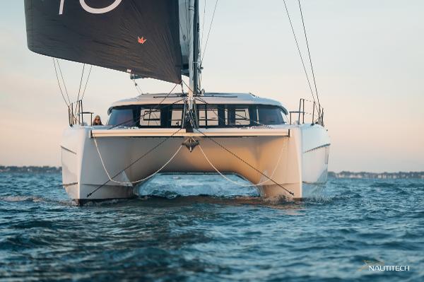 2025 Nautitech 48 Open catamaran sailing on open water at sunset.