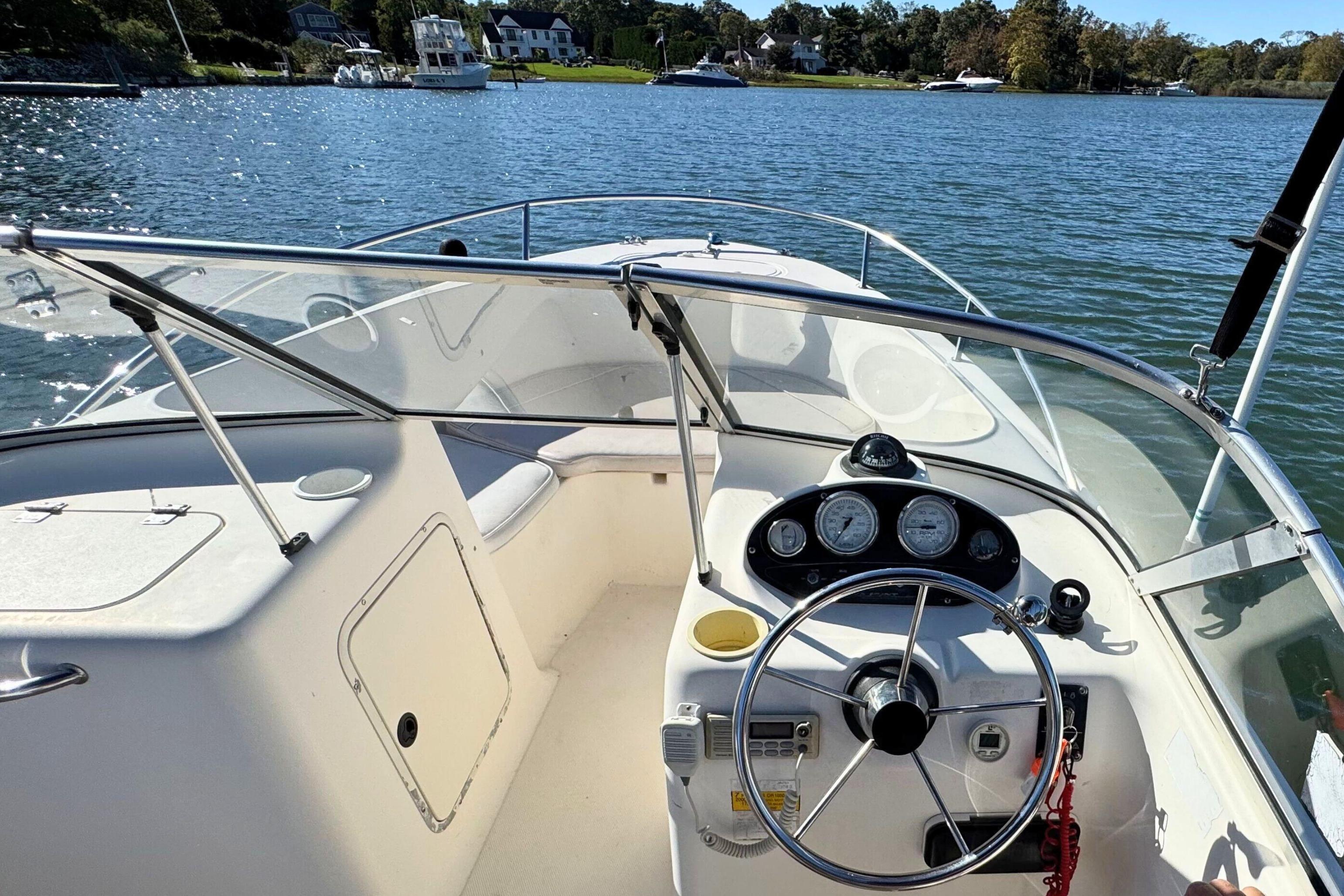 2002 Sea Hunt Escape 200 boat dashboard with steering wheel, gauges, and lake view.