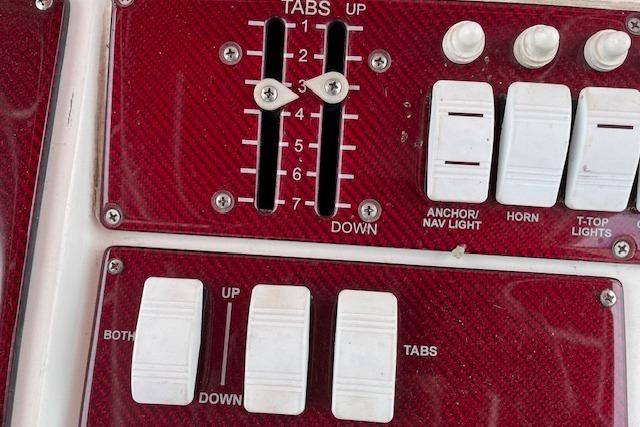 Control panel of a 2001 Fountain 38 Center Console boat with switches and trim tabs.