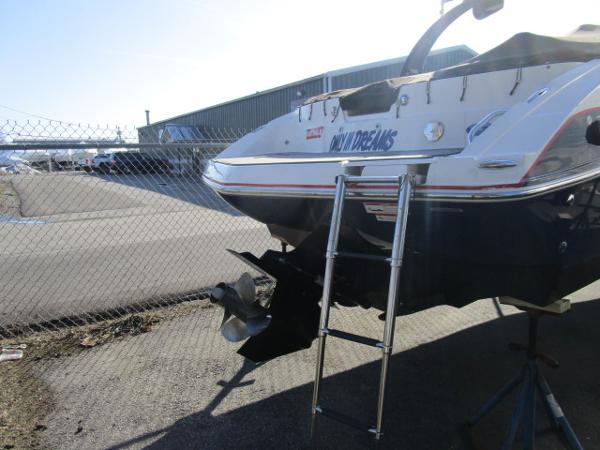 2017 Larson 292 LXI boat with ladder, parked near a chain-link fence.