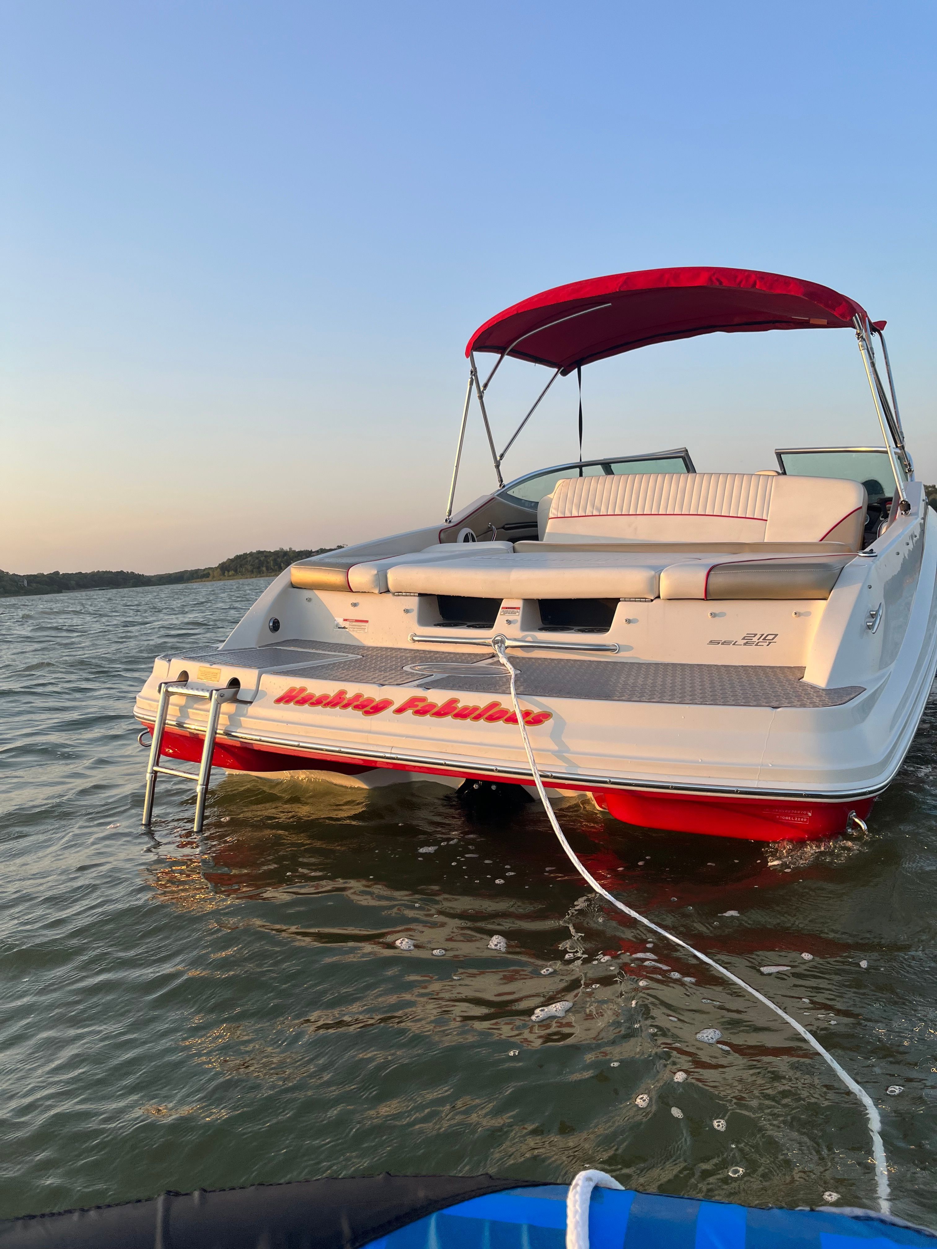 A 2007 Sea Ray 210 Select boat with a red sunshade on calm water.