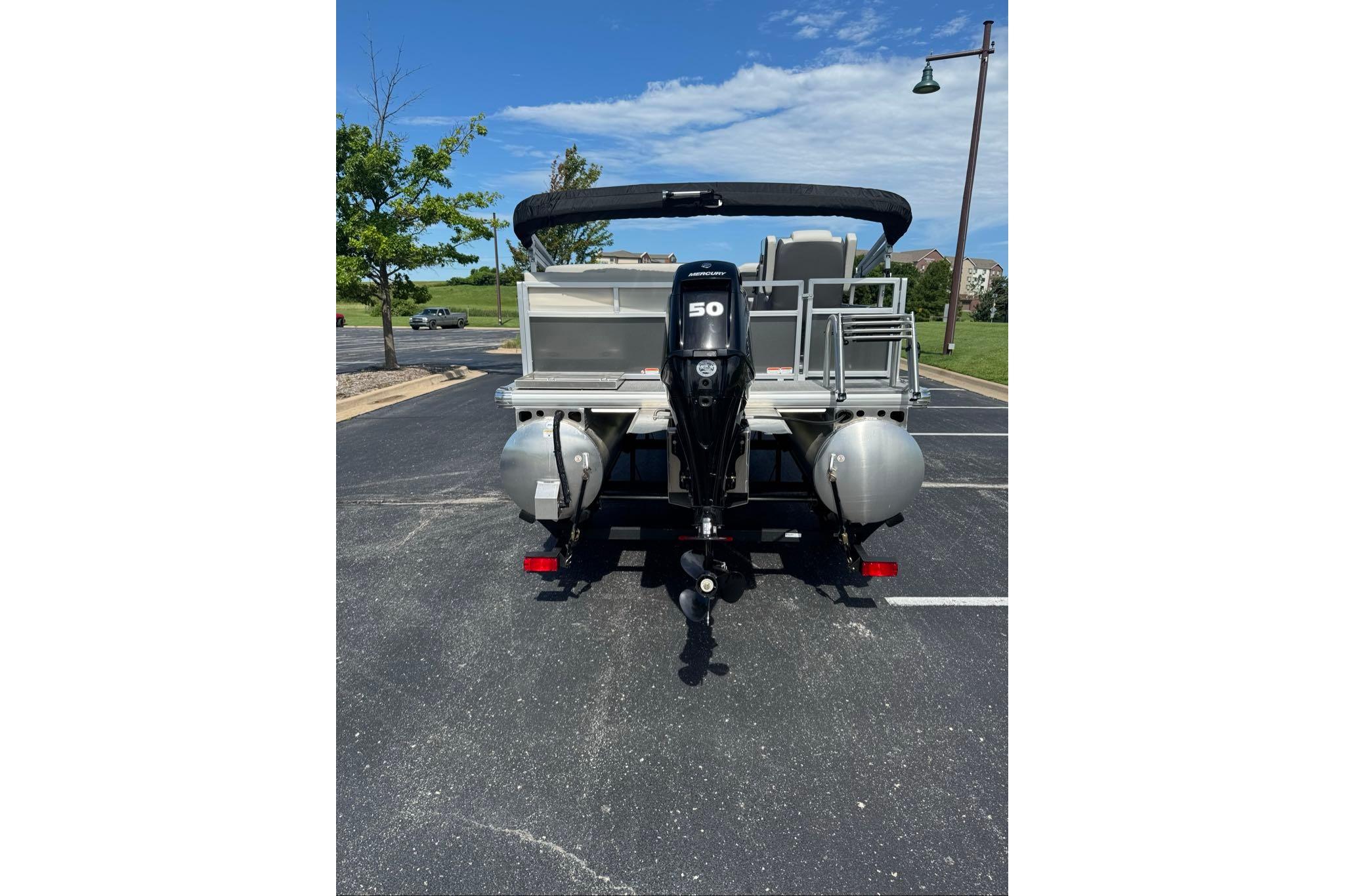 2026 Sun Tracker Bass Buggy 16 XL Select pontoon boat, rear view in parking lot.