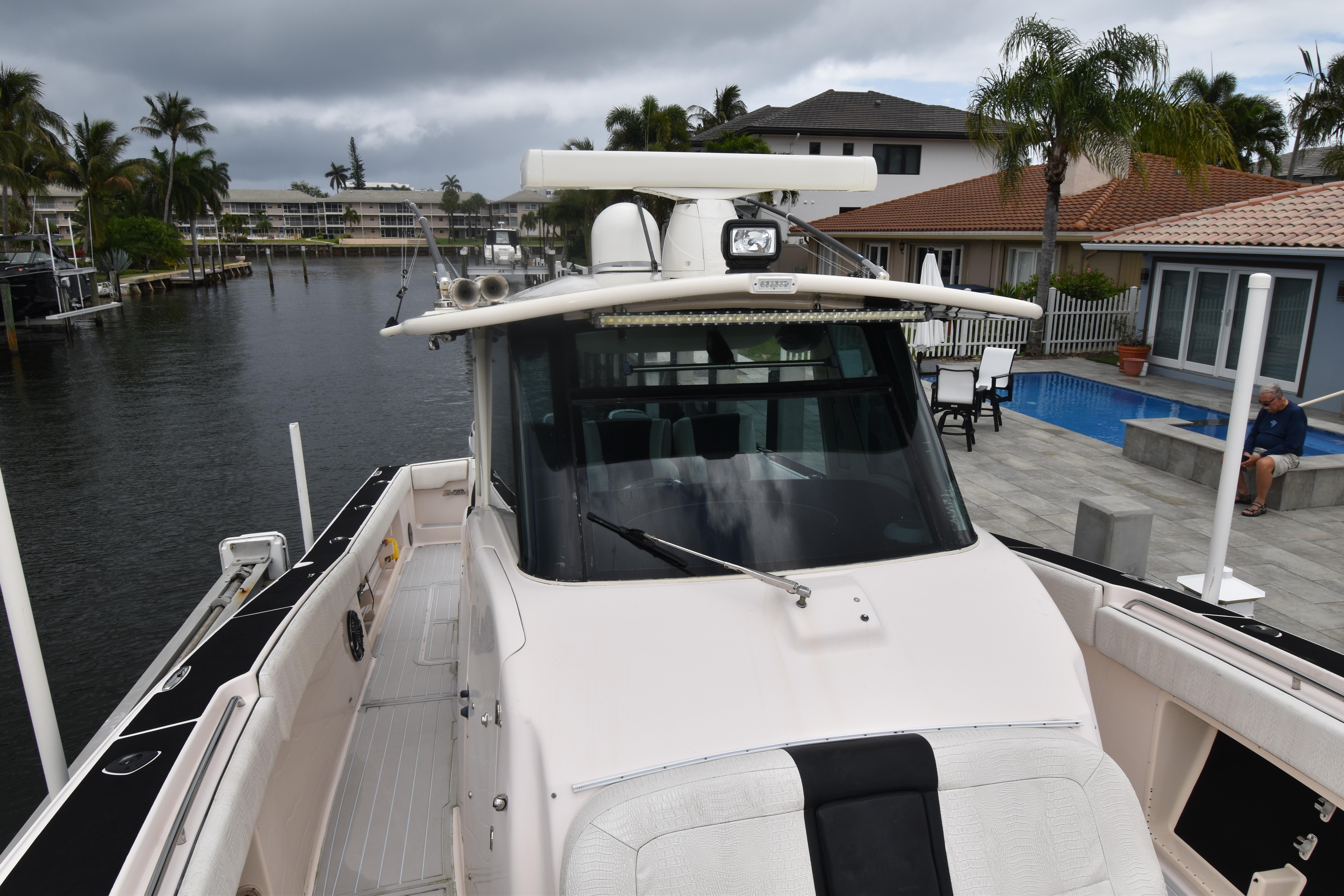 2010 Grady-White Canyon 366 boat docked near waterfront homes and palm trees.