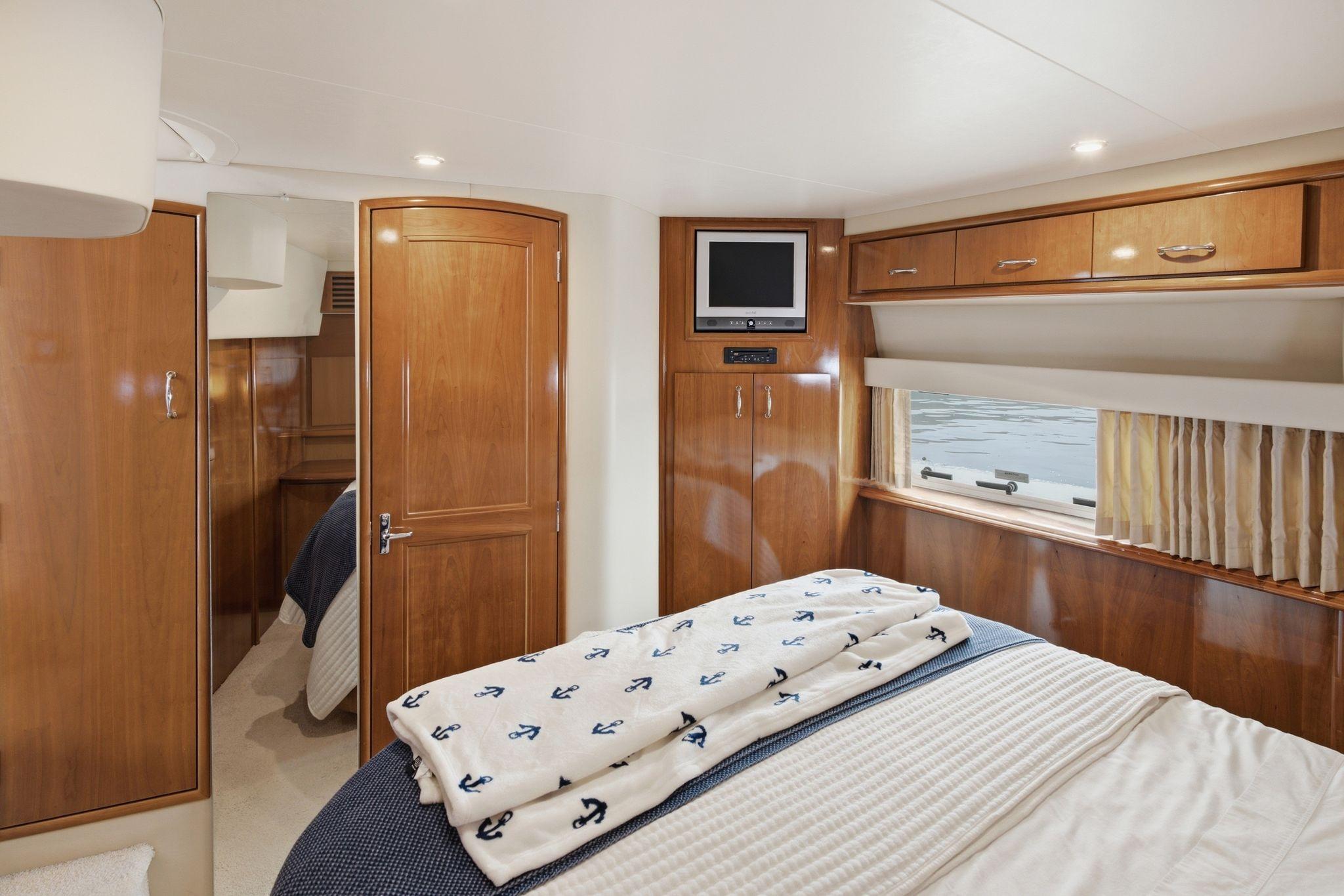 Luxurious cabin interior of 2005 Carver 39 Motor Yacht with wood finishes and cozy bedding.