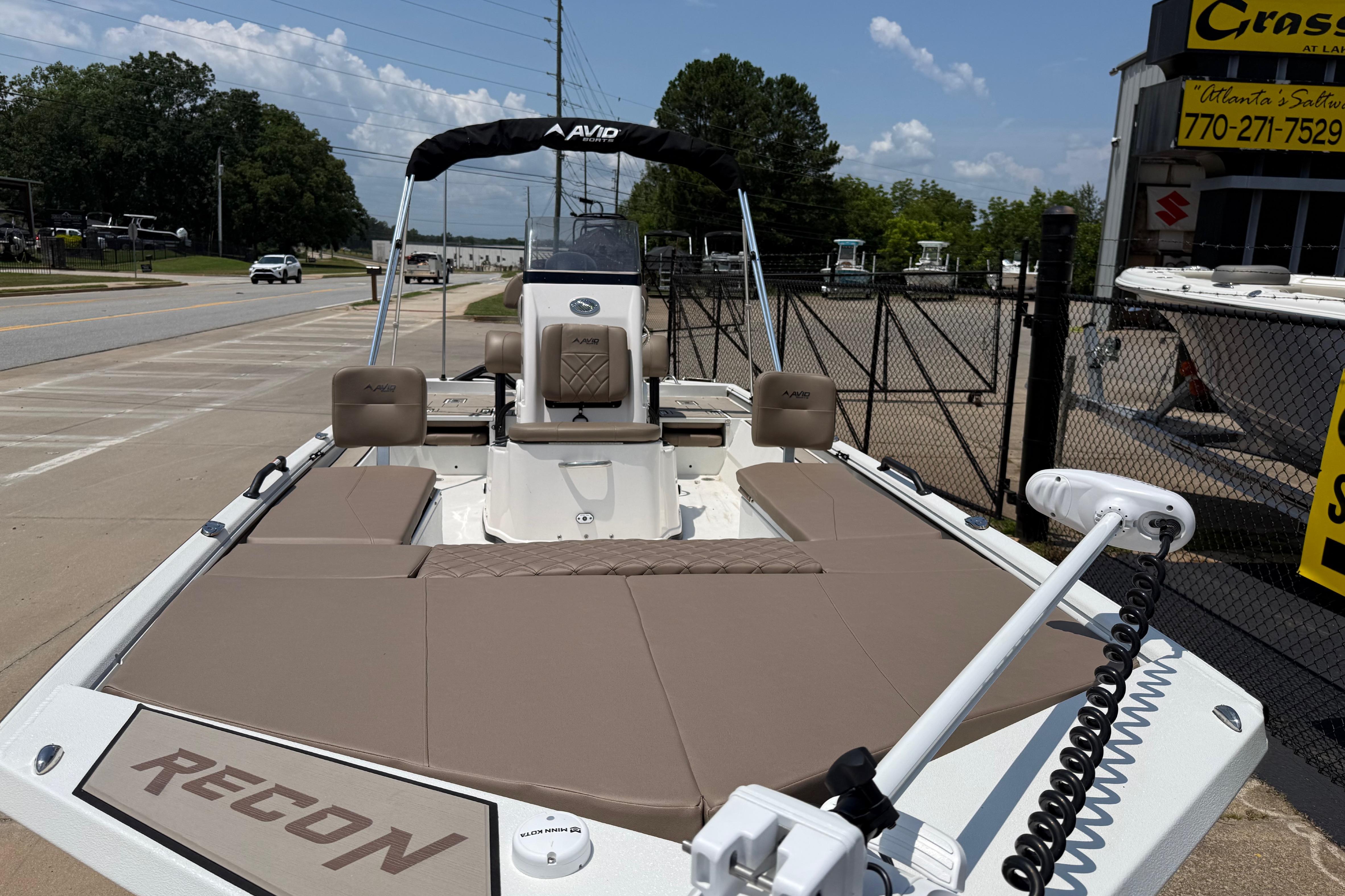2025 Avid 22 Recon boat with tan seating, parked near a dealership on a sunny day.
