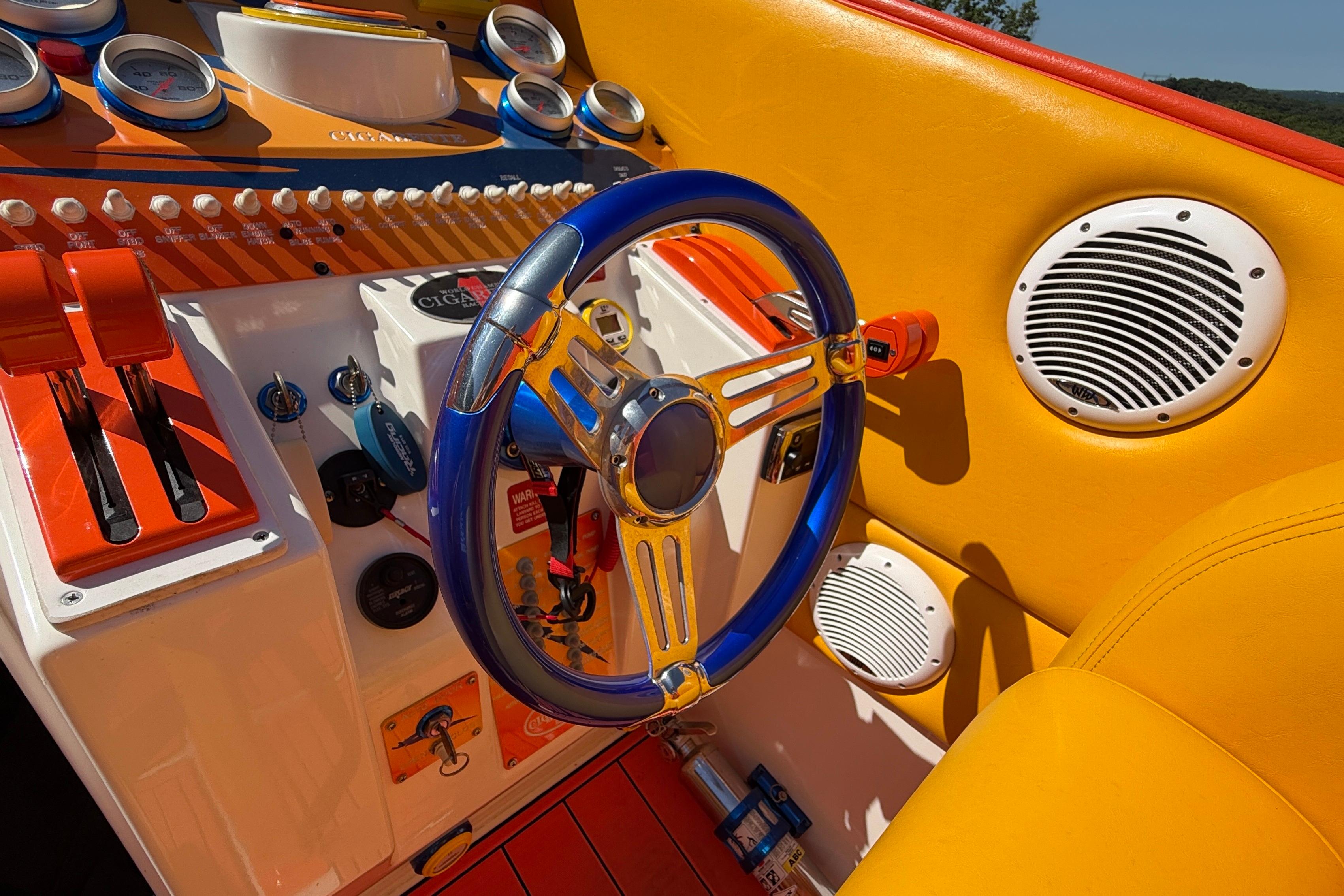 Colorful cockpit of a 2002 Cigarette 35' Cafe Racer boat with vibrant controls and steering wheel.