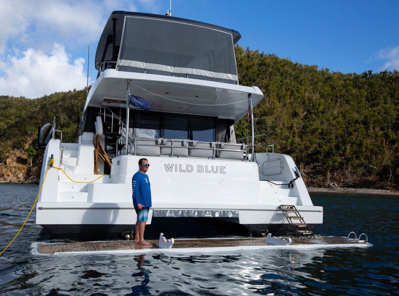 2019 Fountaine Pajot MY 44 yacht "Wild Blue" anchored near lush coastline.