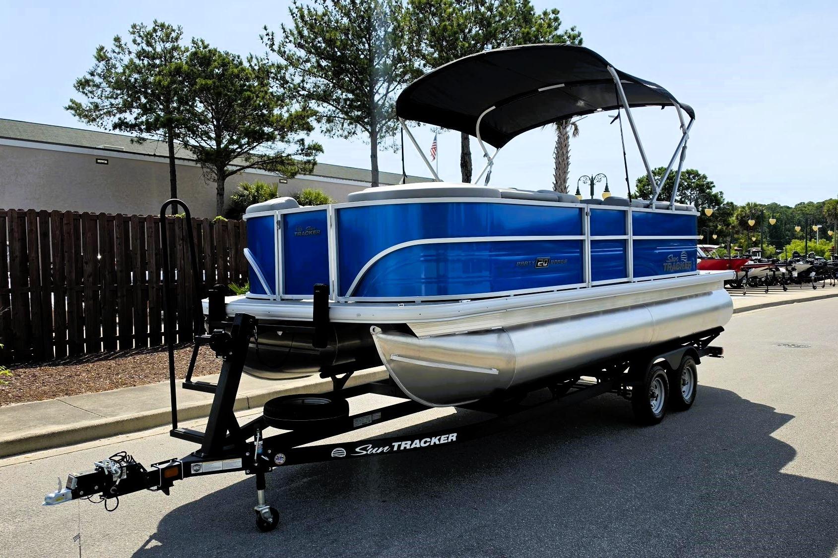 2026 Sun Tracker Party Barge 20 DLX pontoon boat on trailer, parked outdoors.
