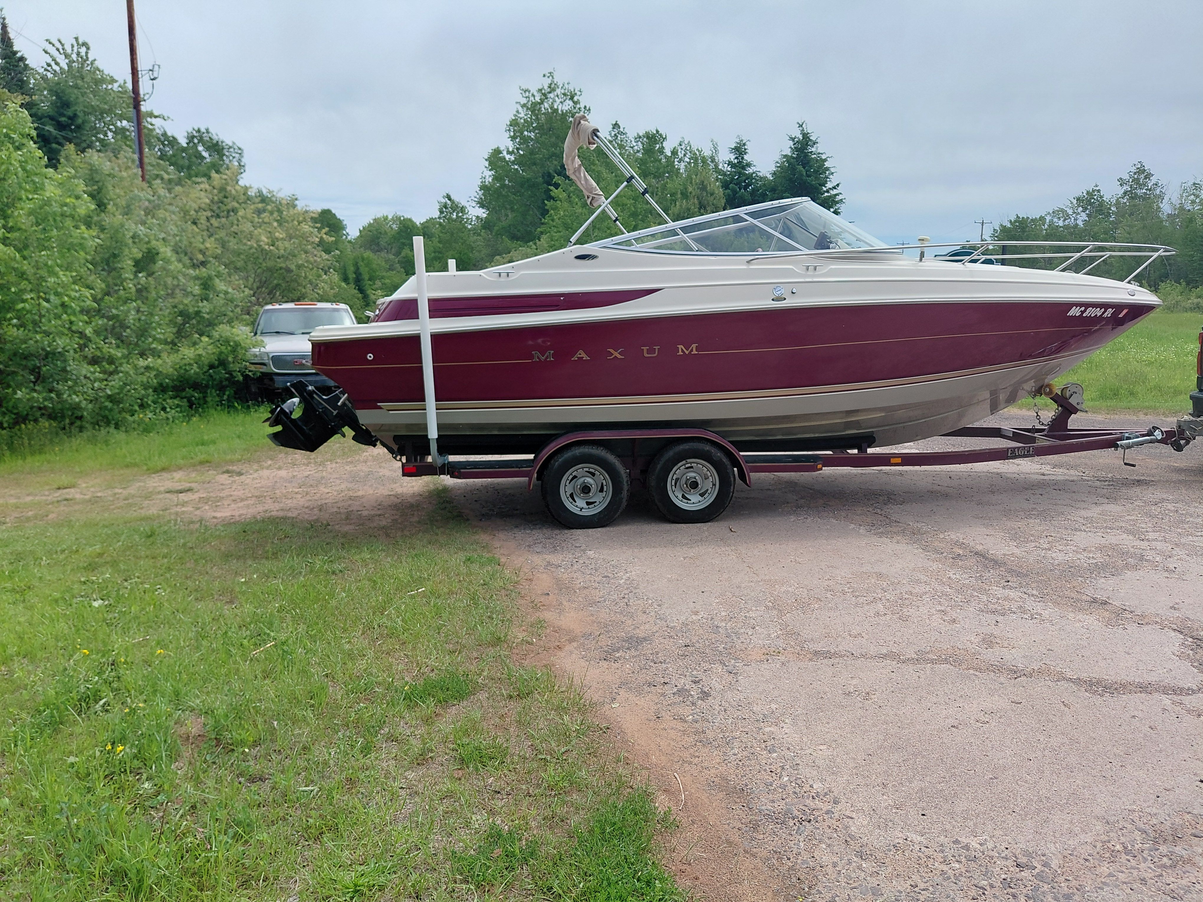 A 1997 Maxum 2300 SC boat on a trailer in a grassy area.