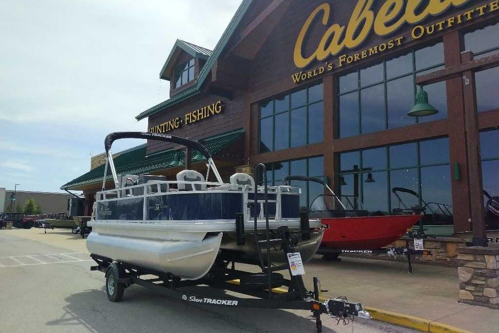 2026 Sun Tracker Bass Buggy 16 XL Select pontoon boat outside Cabela's store.