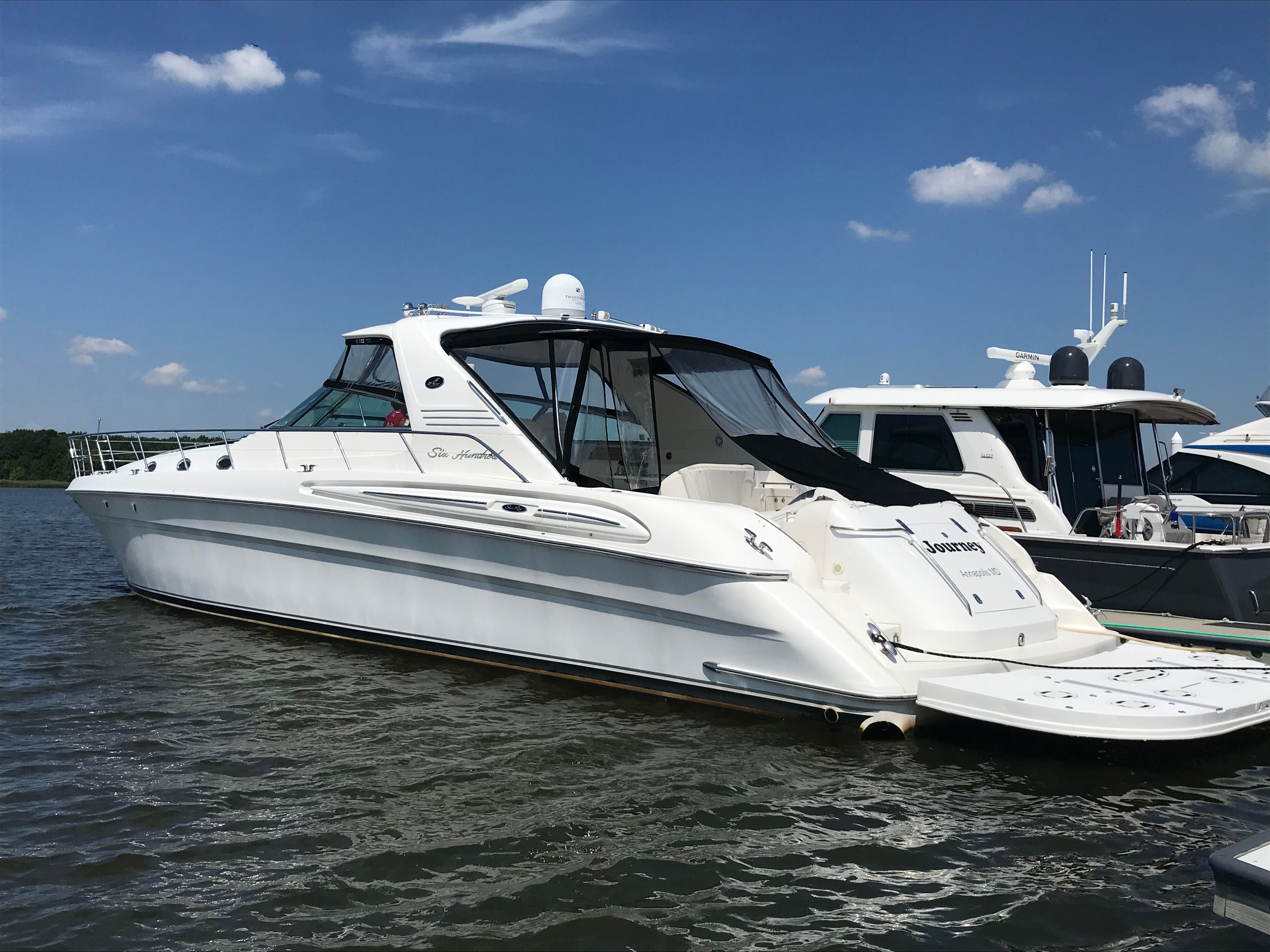 A white 2003 Sea Ray S600 Sunsport is docked on the water next to other boats.