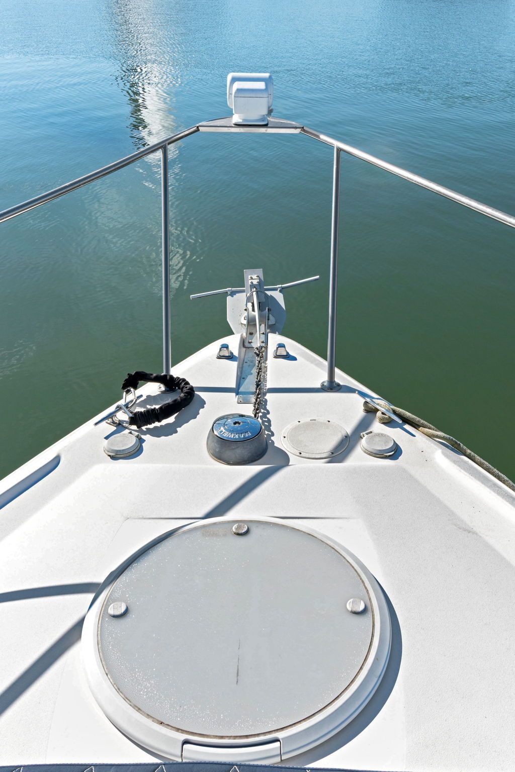 The bow of a boat with anchor and chain, surrounded by calm water.