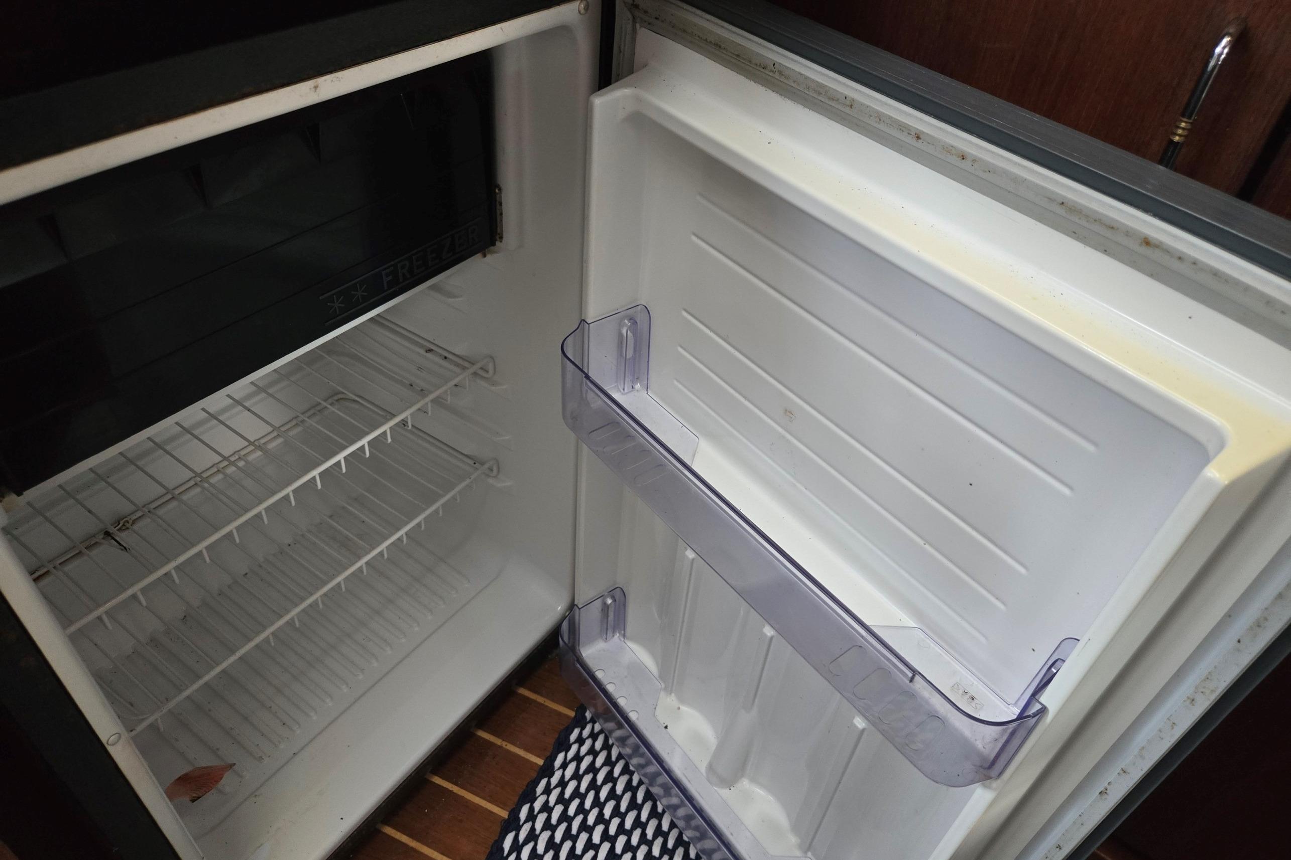 Empty refrigerator inside a 1992 Bayliner 3288 Motoryacht, featuring wire shelves and door storage.