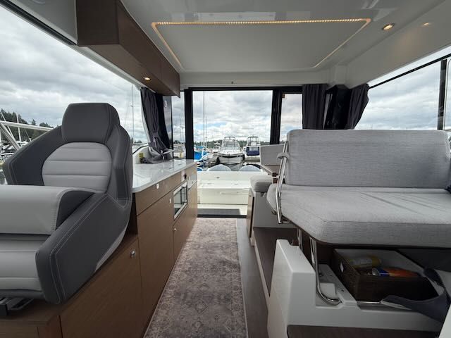 Interior of a 2021 Jeanneau NC 1095 with gray seating and large windows.