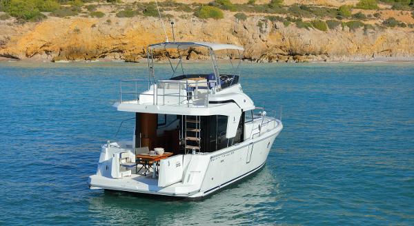 Beneteau Swift Trawler 35, 2021, on calm water near rocky shore.