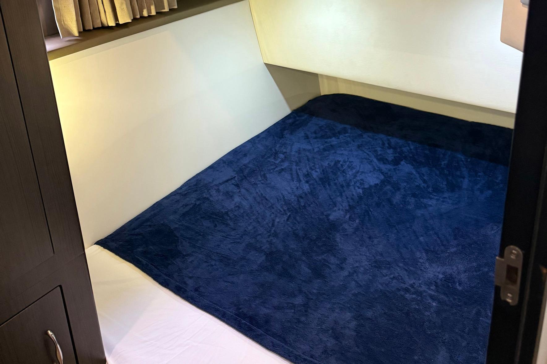 Interior cabin of 2013 Carver C34 yacht with blue bedding and wooden cabinetry.