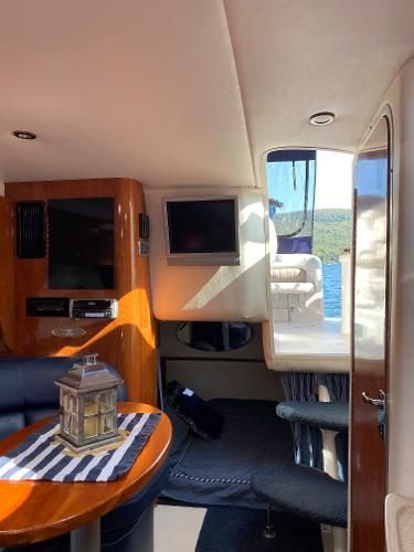 Interior of a yacht with a wooden table, TV, and view of the water.