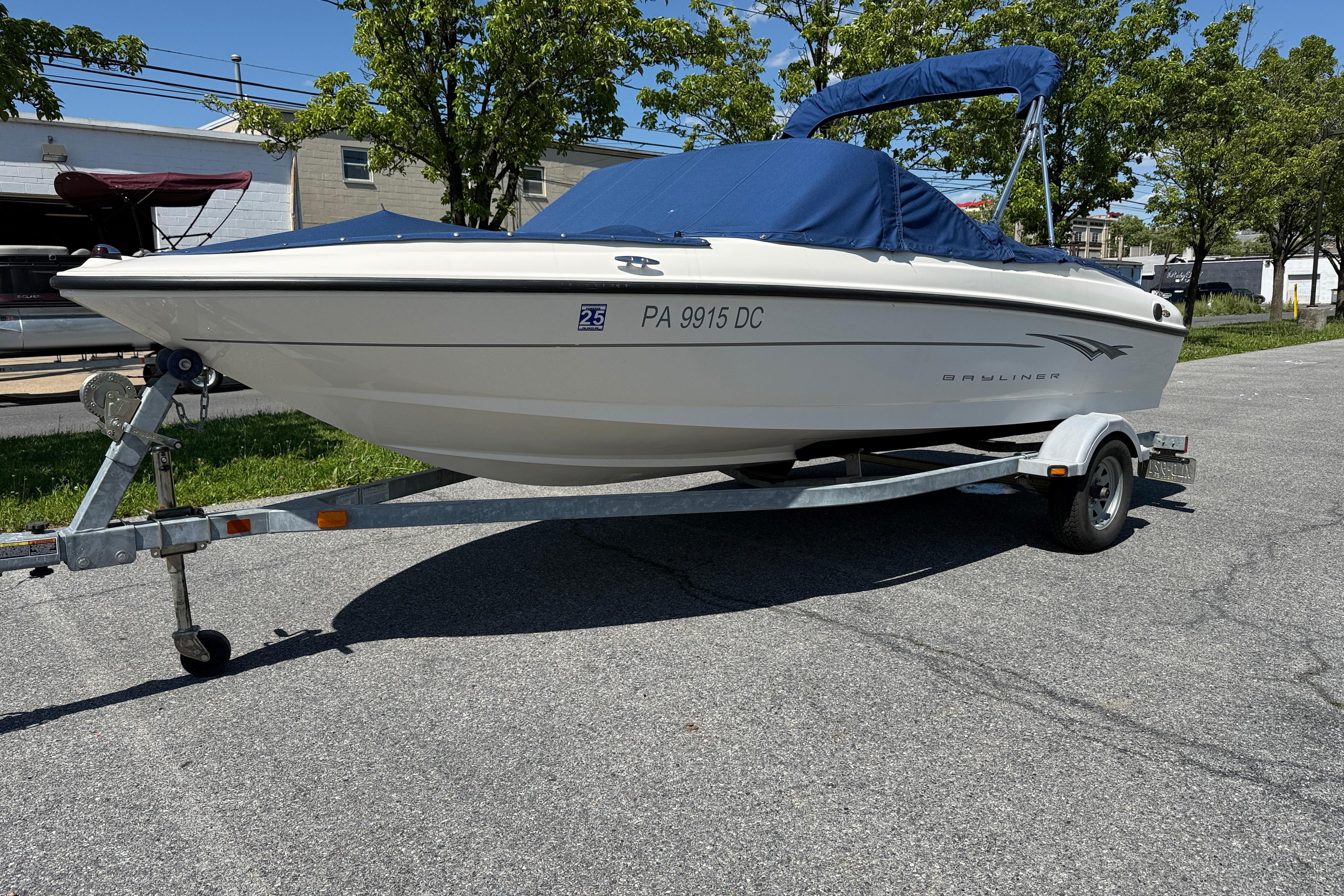 2009 Bayliner 175 boat on trailer with blue cover, parked outdoors.