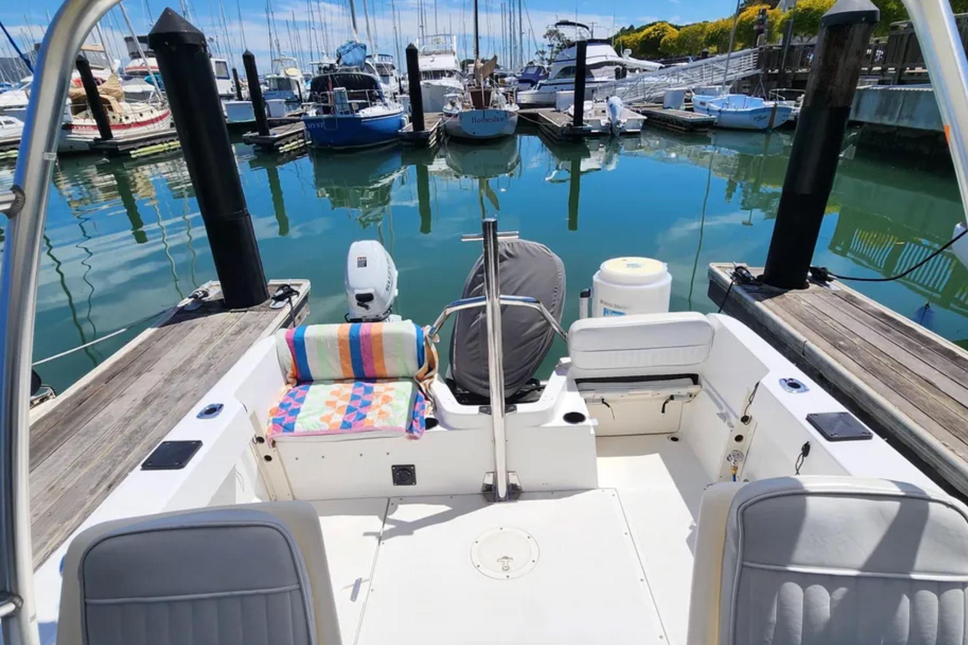 Boston Whaler 21 Conquest 2000 docked at marina, colorful seat cover, calm water reflections.