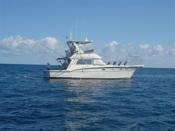 1985 Hatteras 45 Convertible yacht cruising on open sea under clear blue sky.