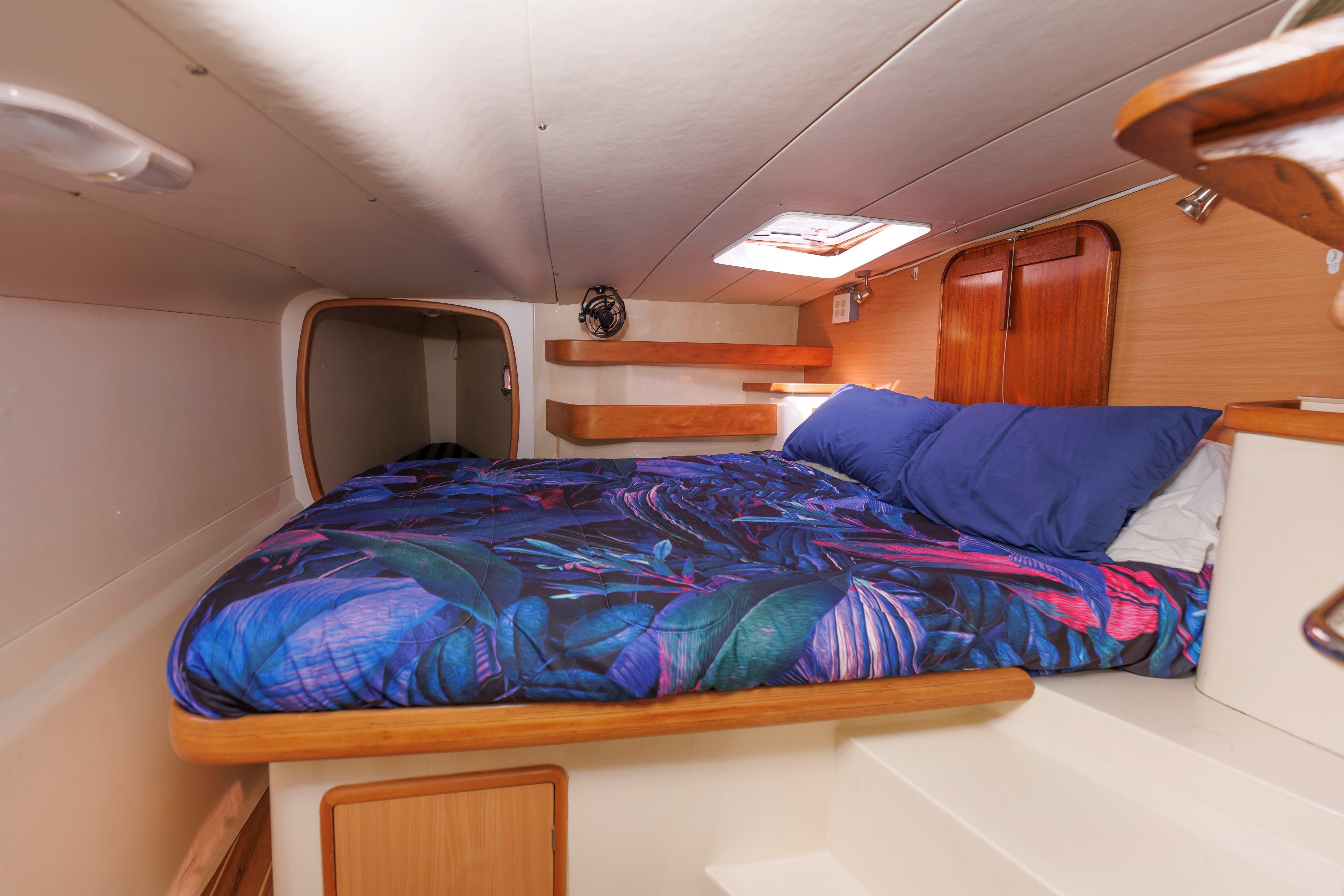 Cozy cabin interior of 2006 Leopard 43 yacht with vibrant bedding and wooden accents.