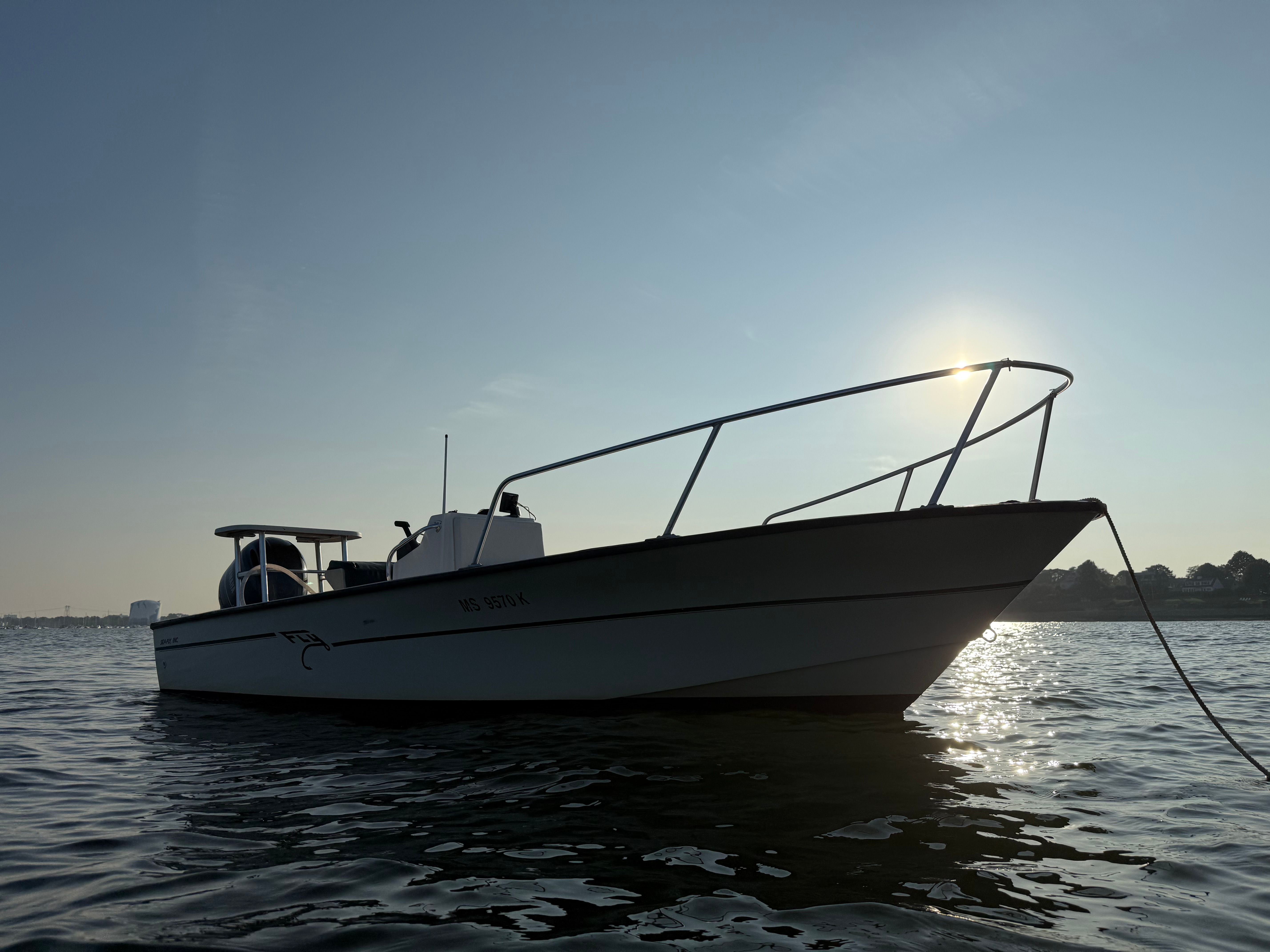 Custom 2004 Sea Fly boat silhouetted against sunrise on calm water.