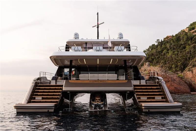 2026 Sunreef 80 Sunreef Power yacht on water, rear view, near rocky coastline.