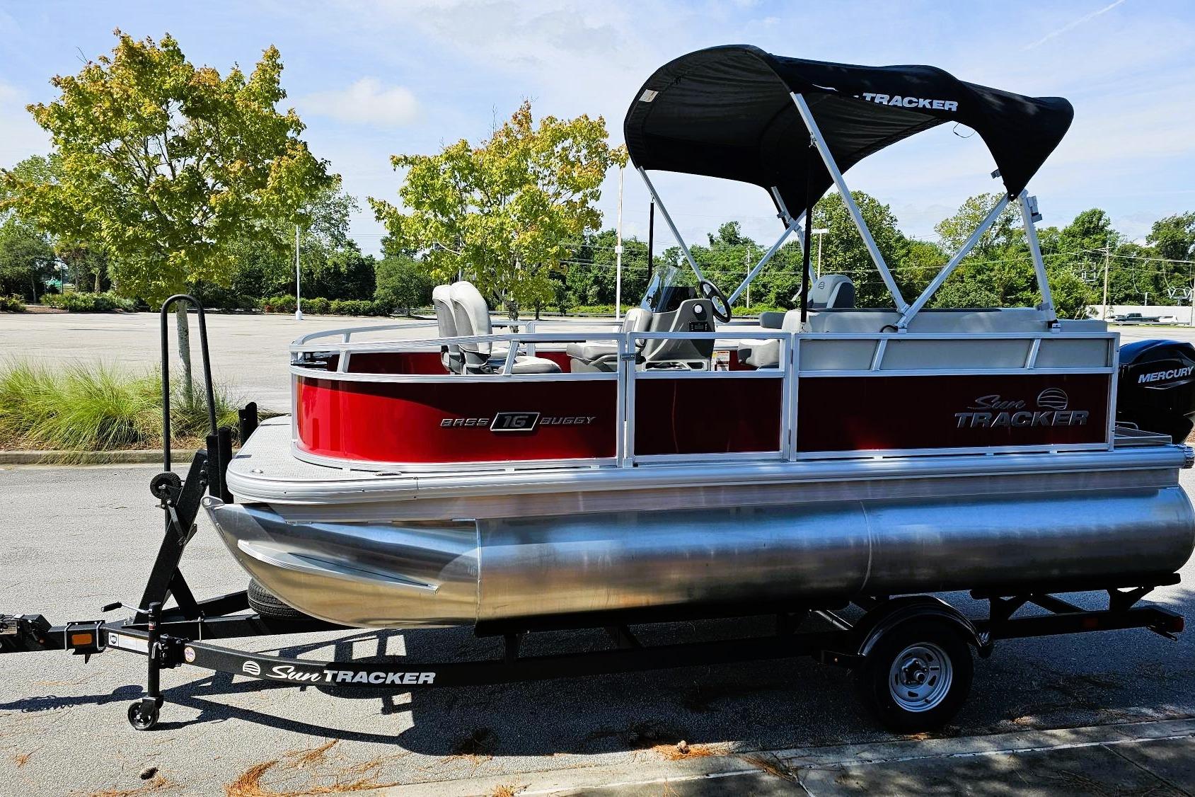 2026 Sun Tracker Bass Buggy 16 XL Select pontoon boat on trailer, parked outdoors.