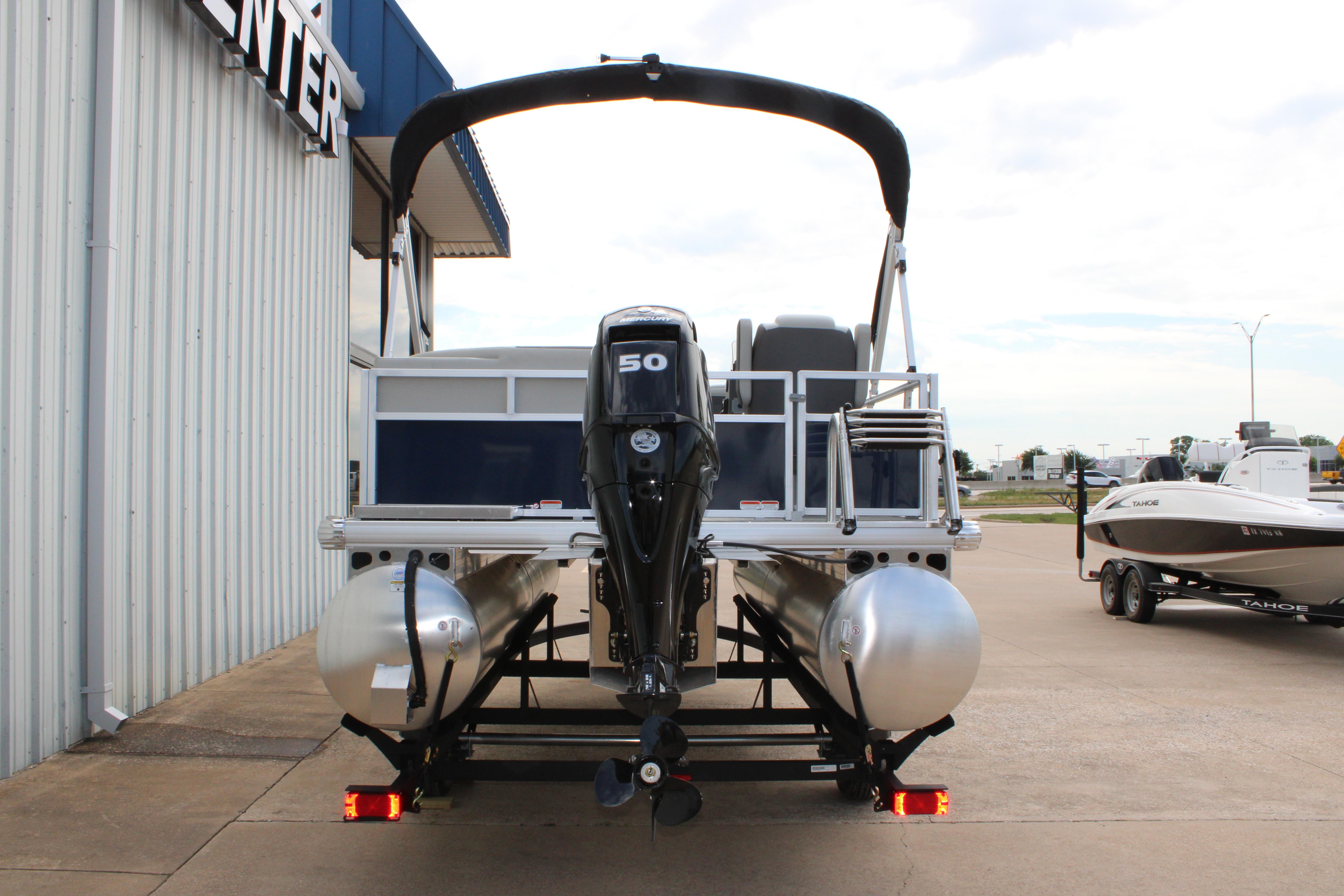 2026 Sun Tracker Bass Buggy 16 XL Select pontoon boat with outboard motor, parked outdoors.