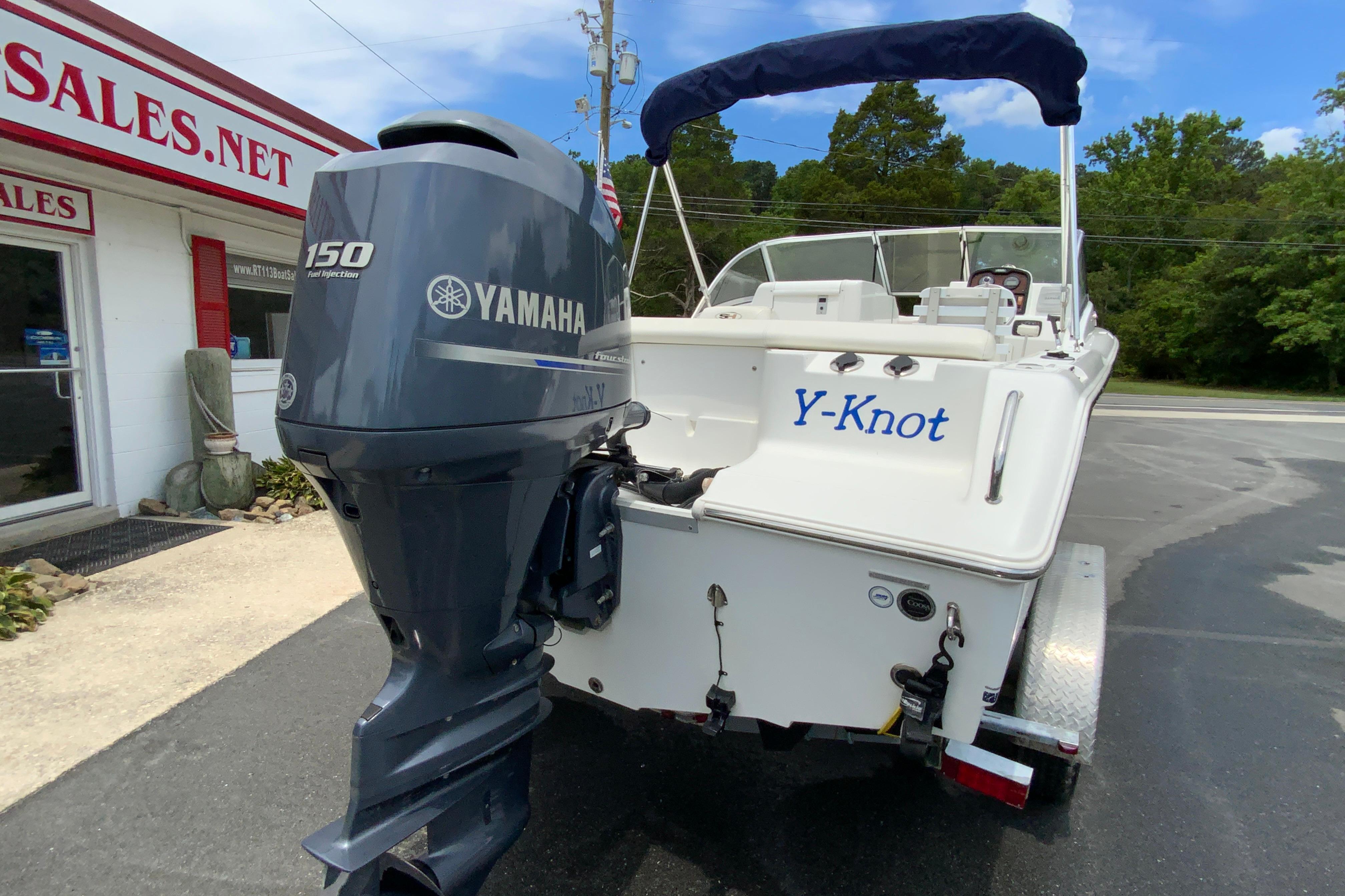2014 Sea Hunt Escape 211 LE boat with Yamaha 150 engine, parked outside sales building.