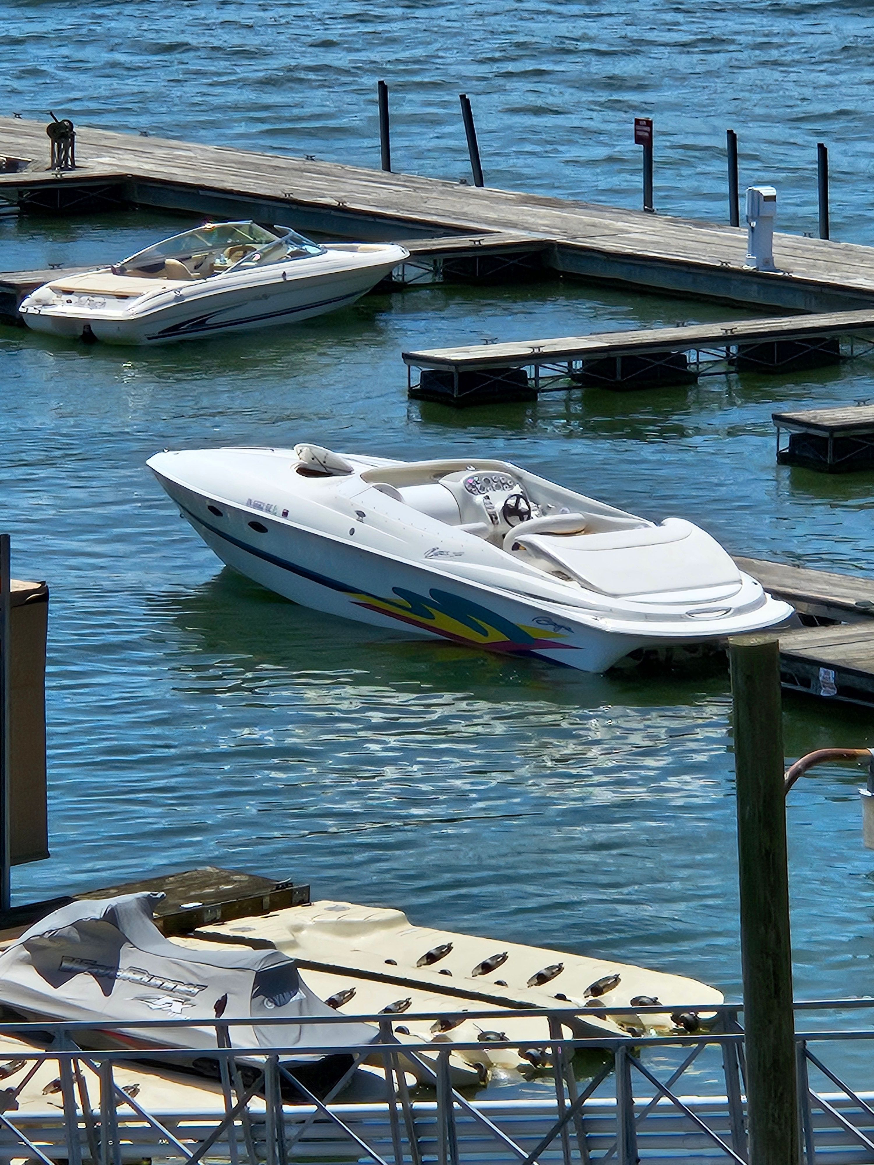 A white speedboat docked, featuring colorful stripes on the side.